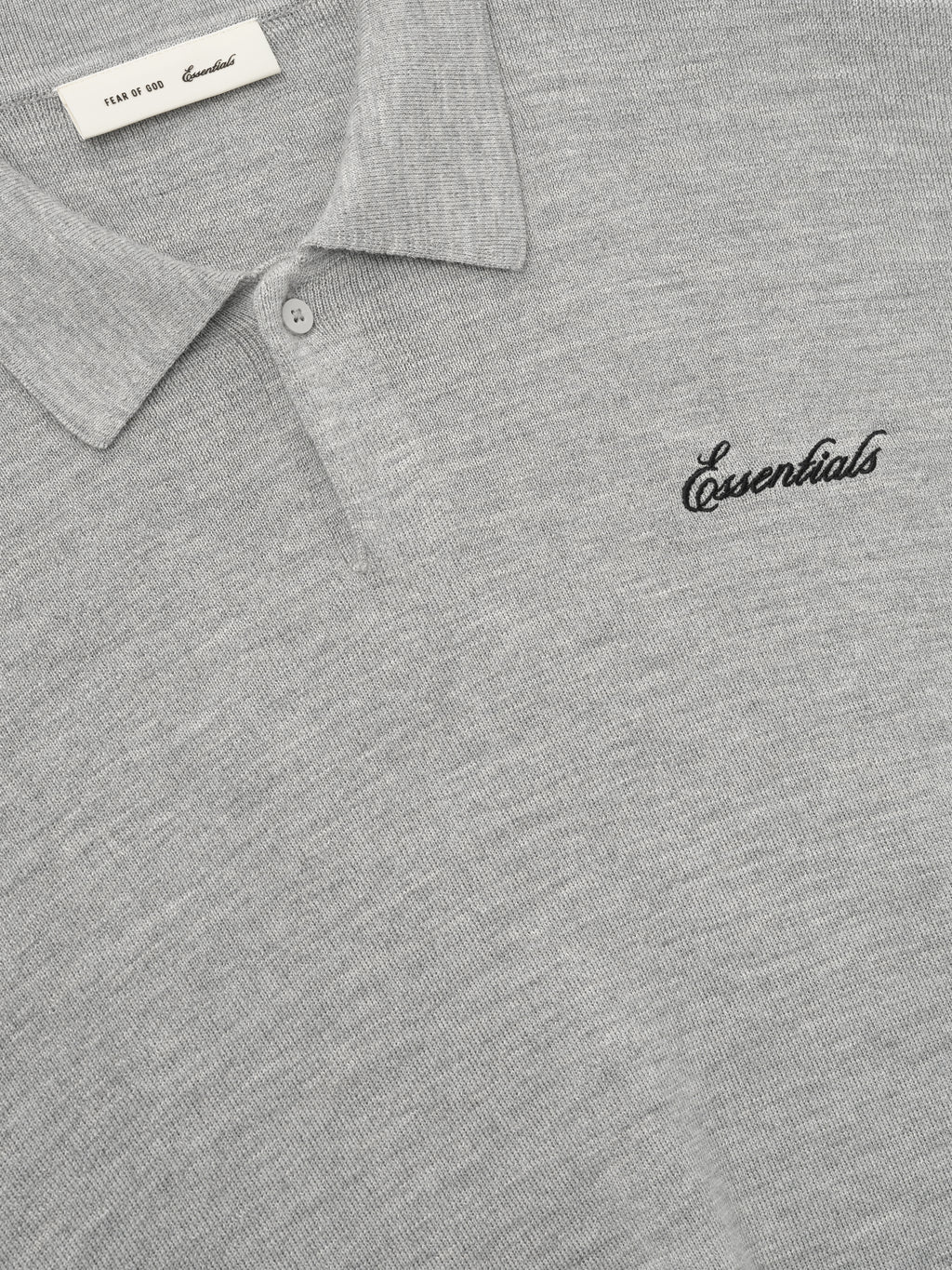 close-up of light grey heavy merino knit polo with classic collar and black Essentials script embroidery on chest