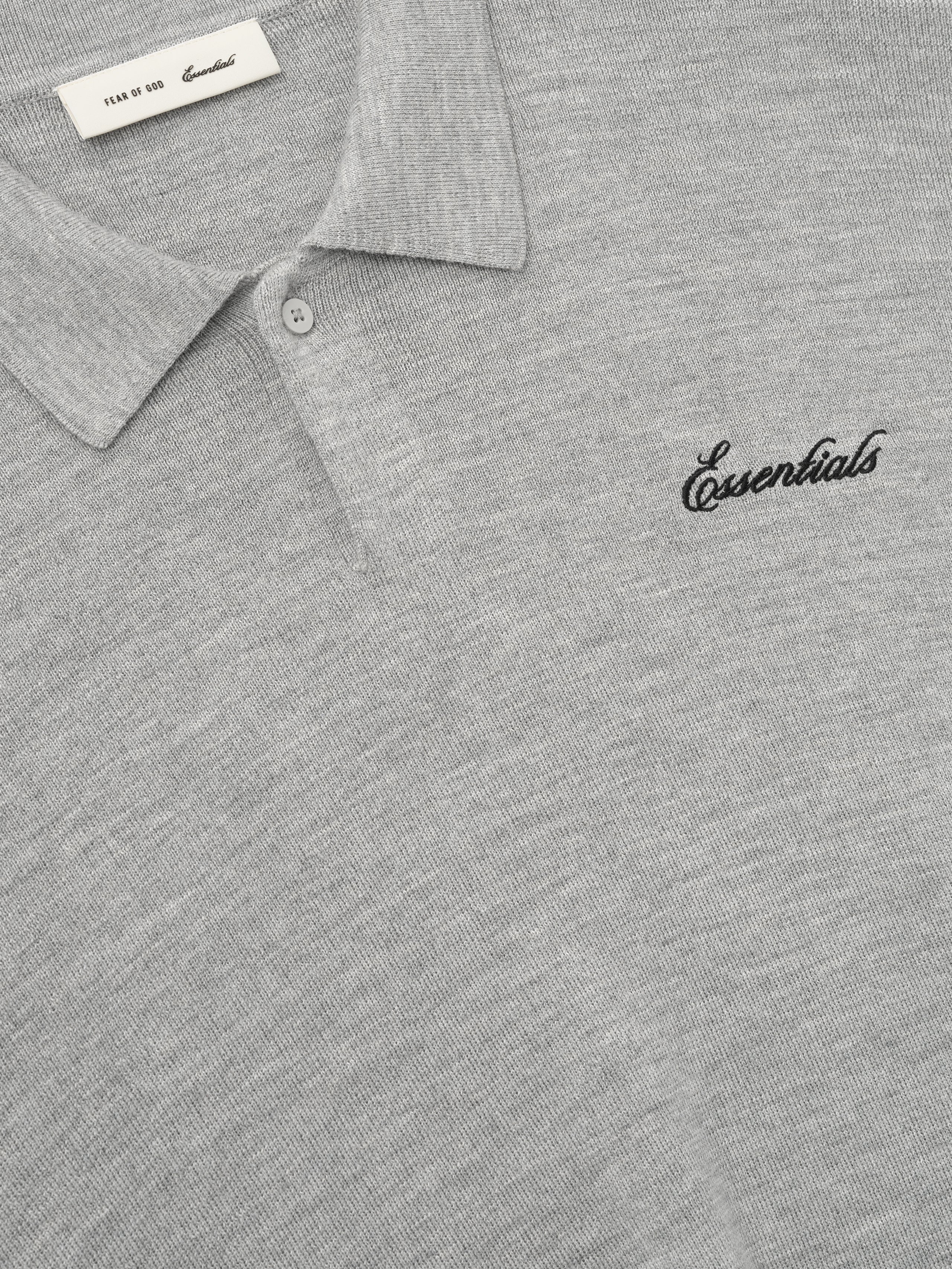close-up of light grey heavy merino knit polo with classic collar and black Essentials script embroidery on chest