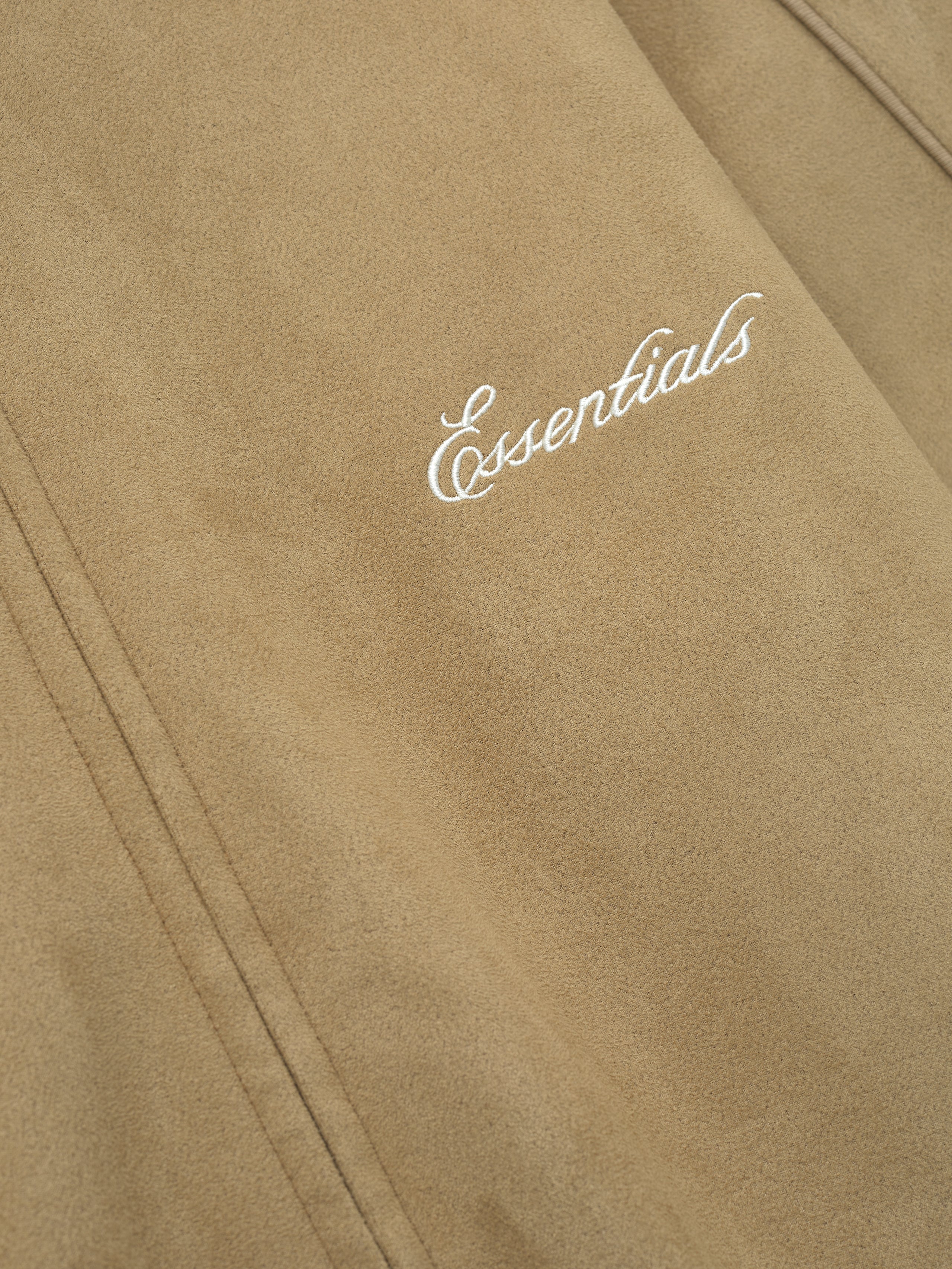 Beige fabric with 'essentials' embroidery on a beige background