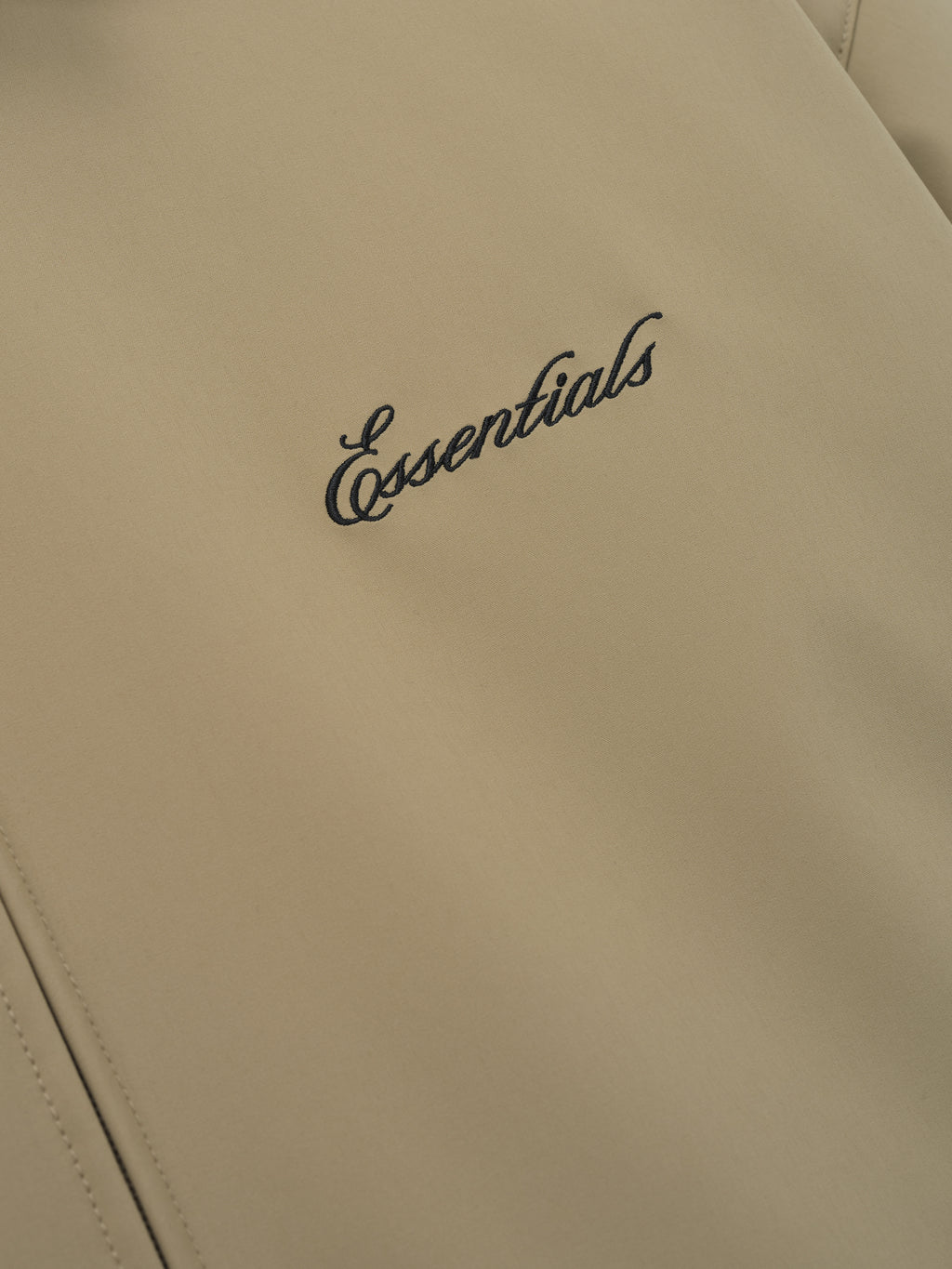 close-up of beige bonded nylon fabric with black Essentials logo embroidered on Signature Filled Barn Jacket