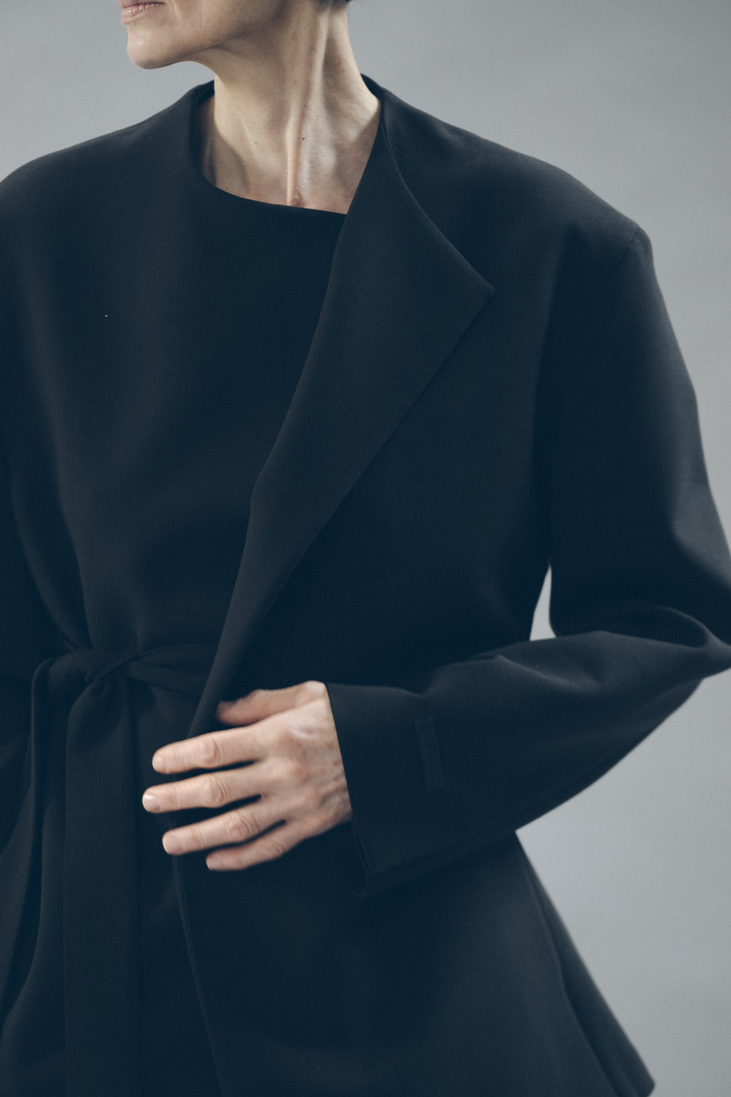 Double Weave Wool Belted Jacket worn in dark navy with a wrap front broad lapels long sleeves and a tied waist as Outerwear