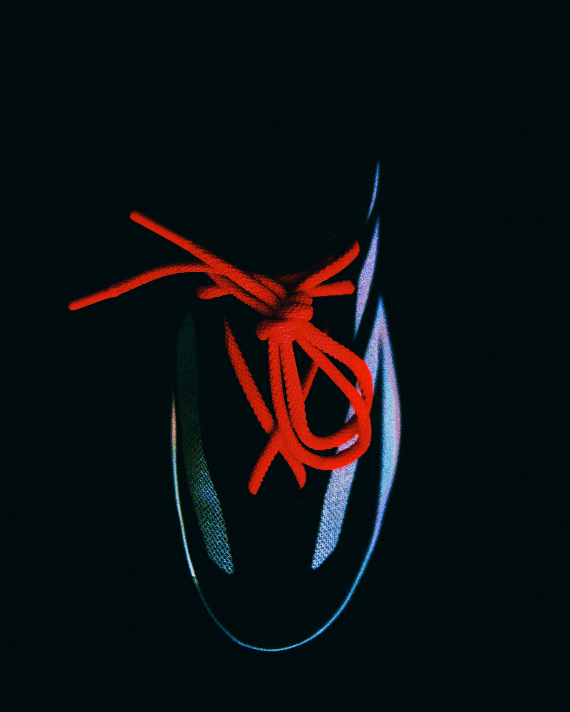 Overhead view of Derrick Rose II Basketball shoe featuring striking red laces and sleek black upper in low light setting