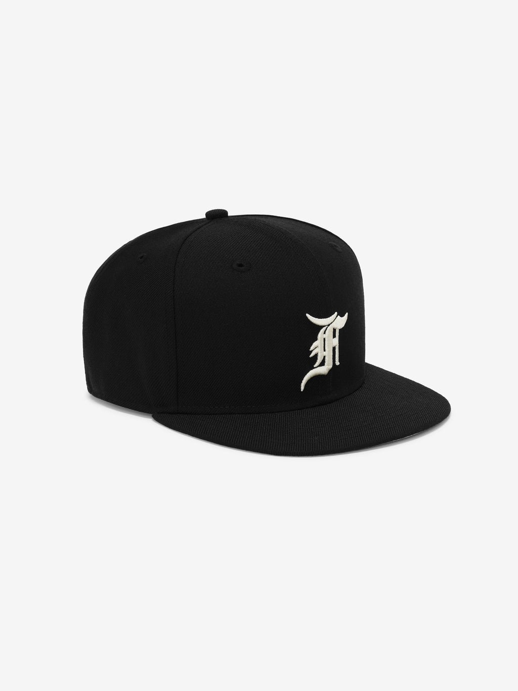 Black structured snapback hat with a cream-colored ornate letter embroidered on front panel against a white backdrop