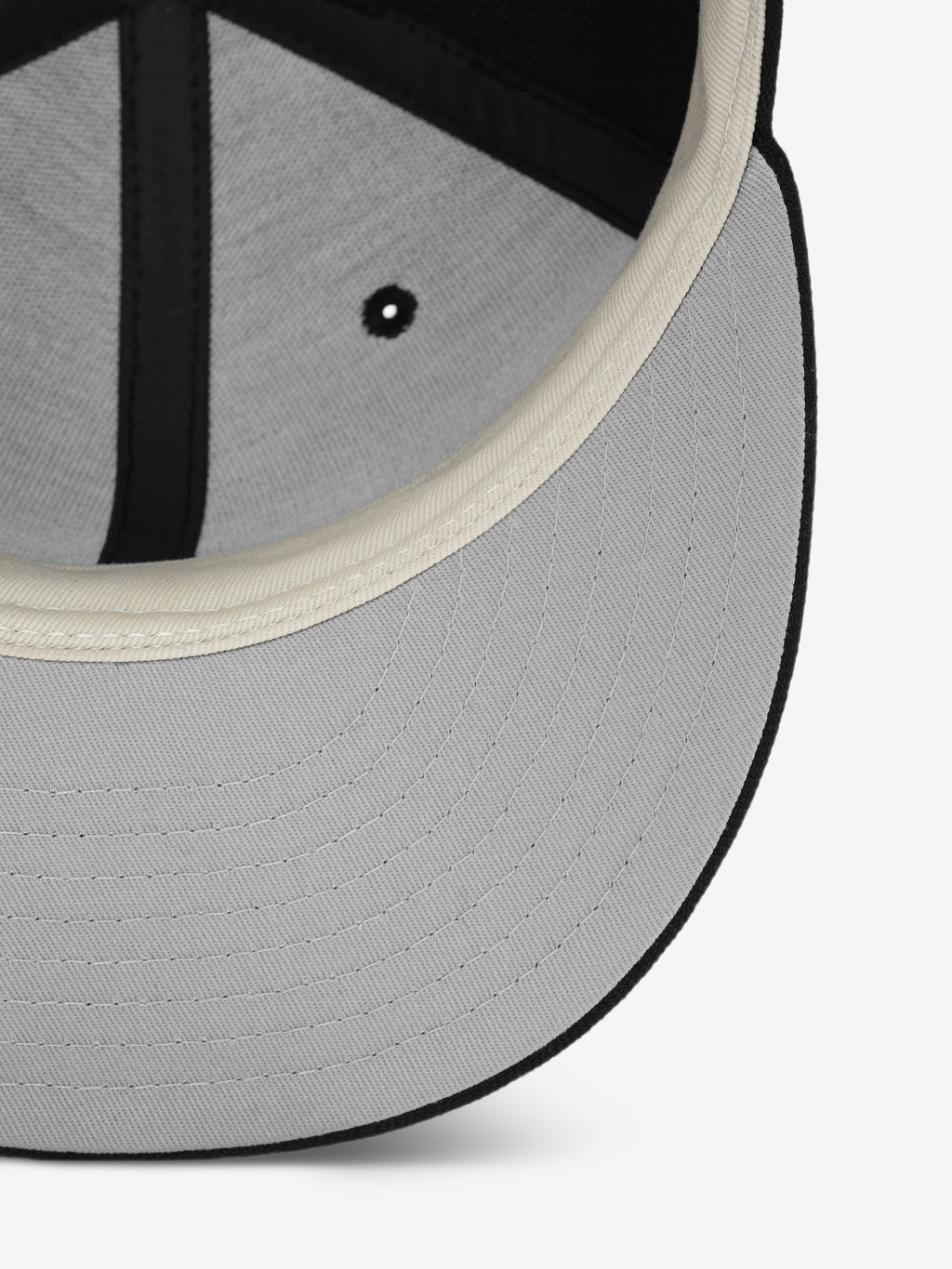 Close-up of the underside of a cap showing a light gray brim with detailed stitching and cream-colored inner lining