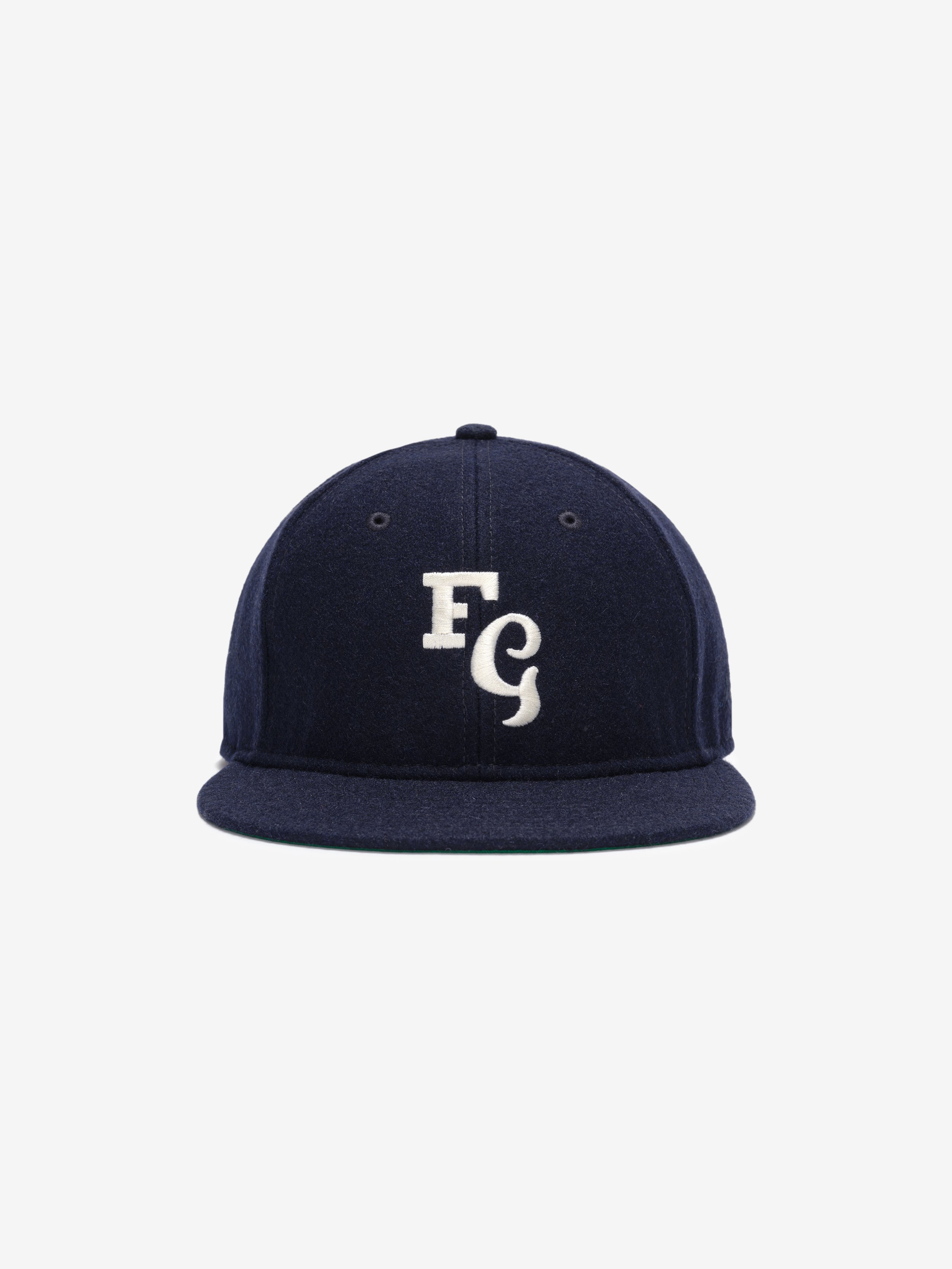 Fear of God Essentials 59FIFTY Retro Fitted FG Cap in deep navy fabric with a white embroidered interlocking "FG" emblem on the front and a structured flat brim.
