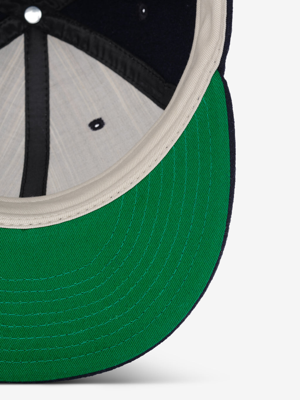 Fear of God Essentials 59FIFTY Retro Fitted FG Cap shown from underneath, highlighting the green underside of the brim with cream and black inner stitching details.