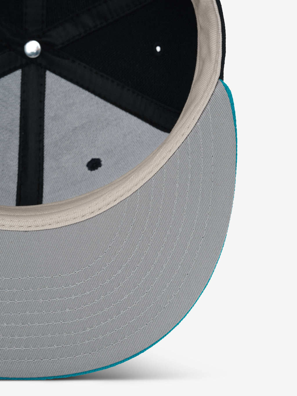 Fear of God Essentials 59FIFTY Athletics Cap showing the underside of a light grey brim with detailed stitching and a contrasting turquoise edge, highlighting the interior black panels and beige sweatband.