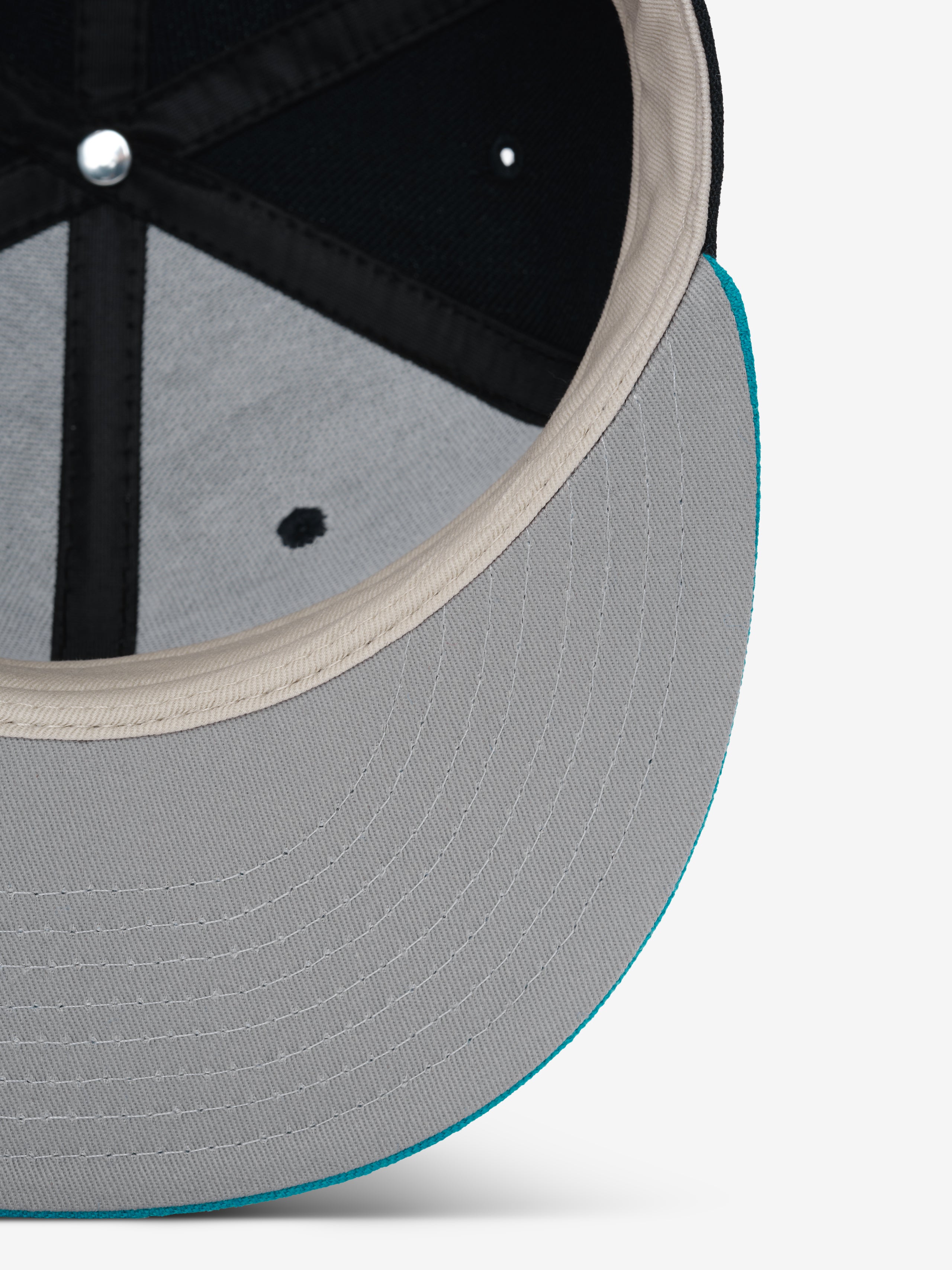 Fear of God Essentials 59FIFTY Athletics Cap showing the underside of a light grey brim with detailed stitching and a contrasting turquoise edge, highlighting the interior black panels and beige sweatband.