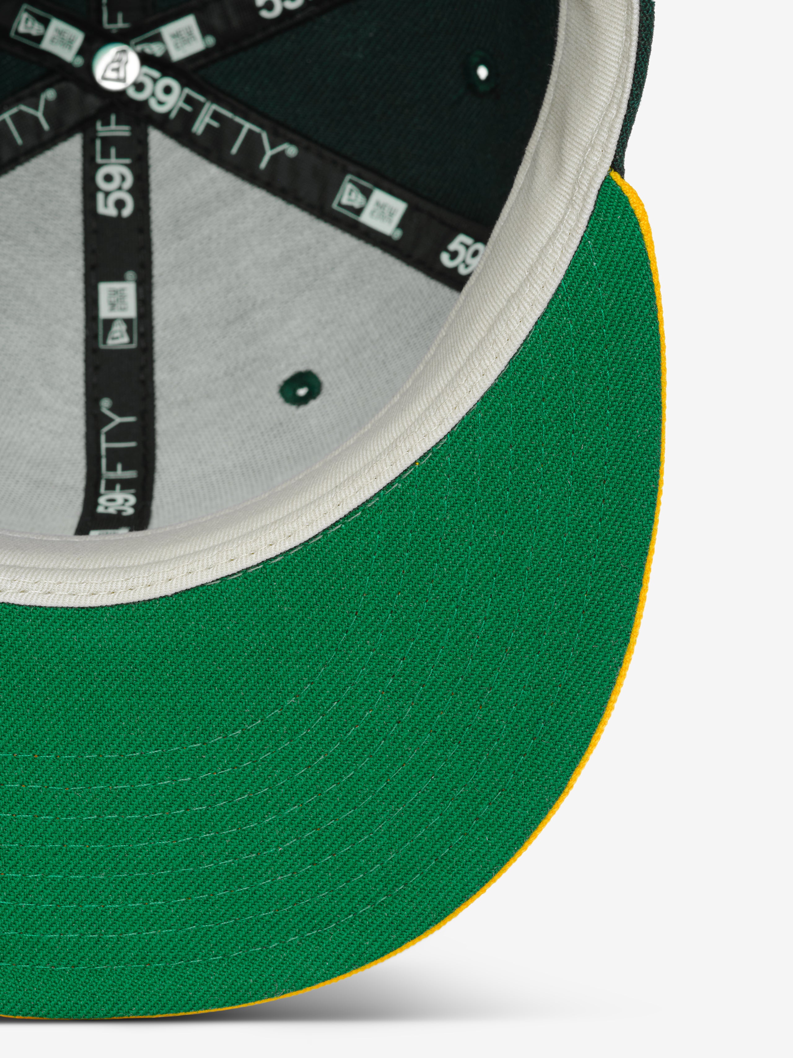 Fear of God Essentials 59FIFTY Athletics Cap showing the underside of the green brim with yellow edging, interior black paneling featuring 59FIFTY branded tape, and beige sweatband.