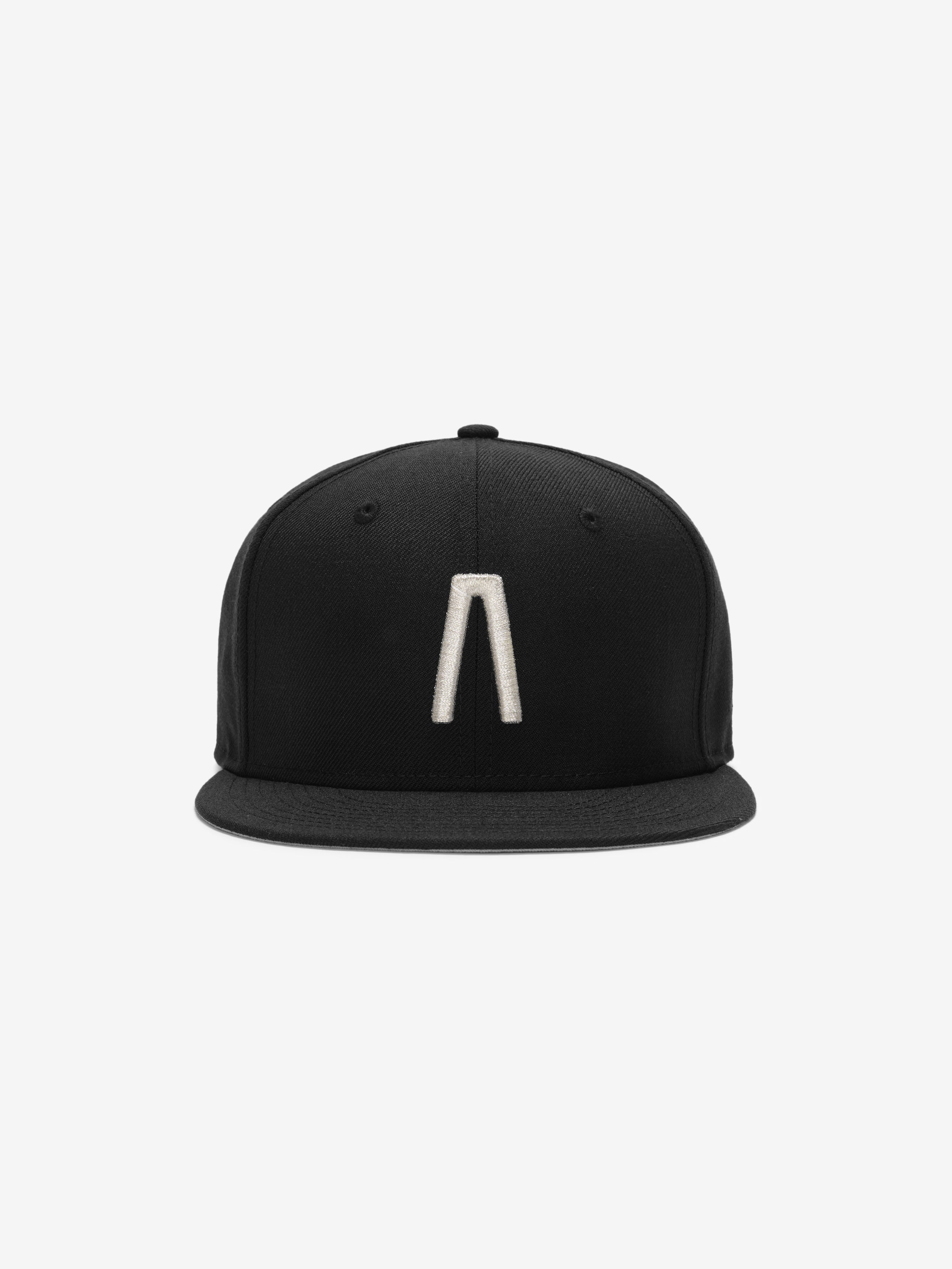 Fear of God Essentials 59FIFTY Athletics Cap featuring a solid black crown with a raised metallic silver minimalist emblem centered on the front and a flat black brim.
