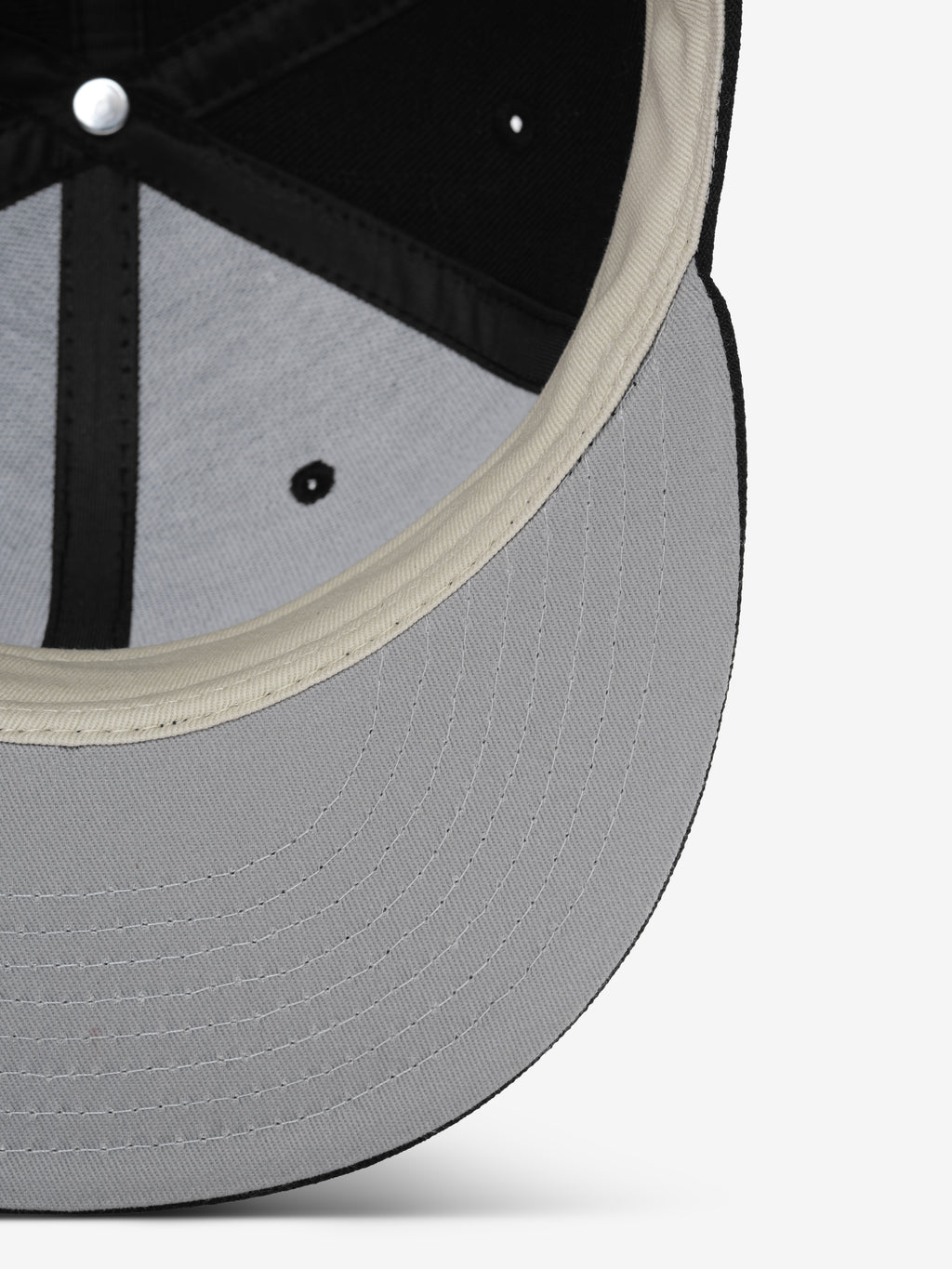 Fear of God Essentials 59FIFTY Athletics Cap featuring a light gray underside brim with multiple rows of stitching and a cream-colored inner sweatband contrasted against a black crown interior.