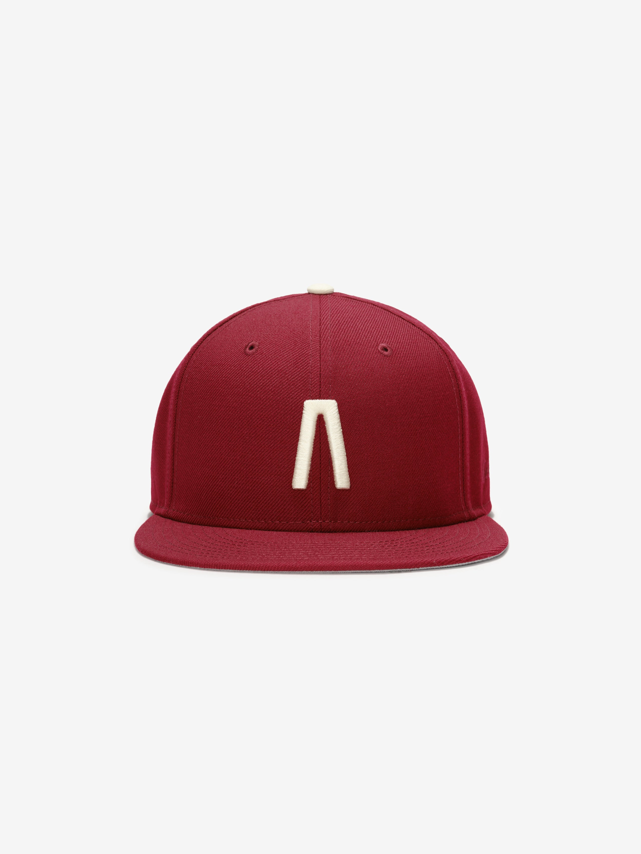 Fear of God Essentials 59FIFTY Athletics Cap in deep crimson featuring a minimalist cream emblem centered on the front panel with a structured flat brim design.