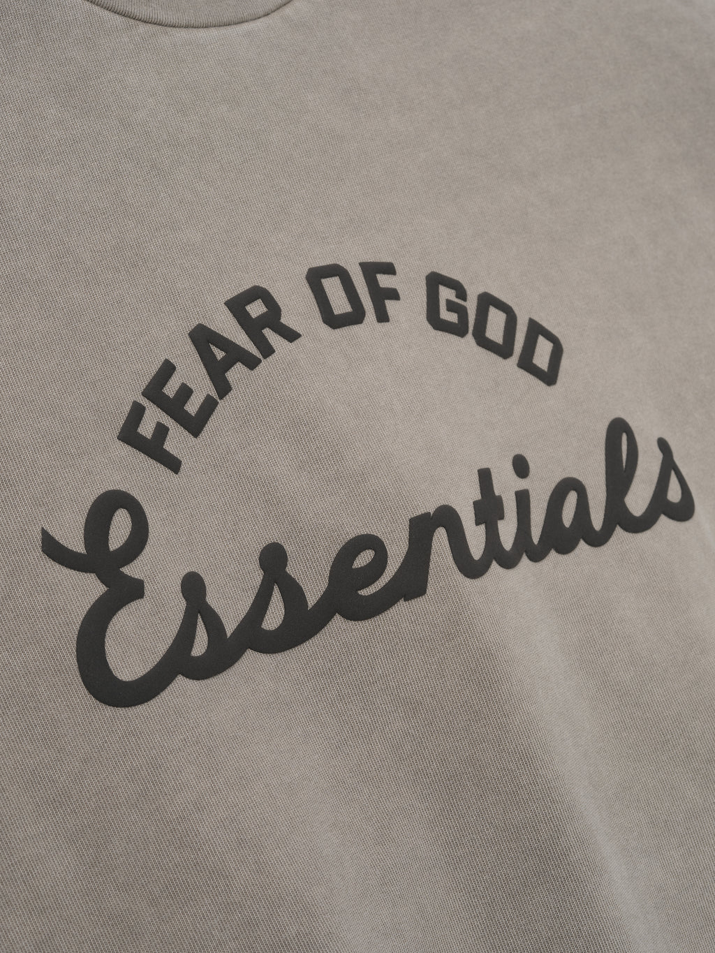 close-up of pigment-dyed heavyweight cotton tee fabric with curved Fear of God Essentials print in black