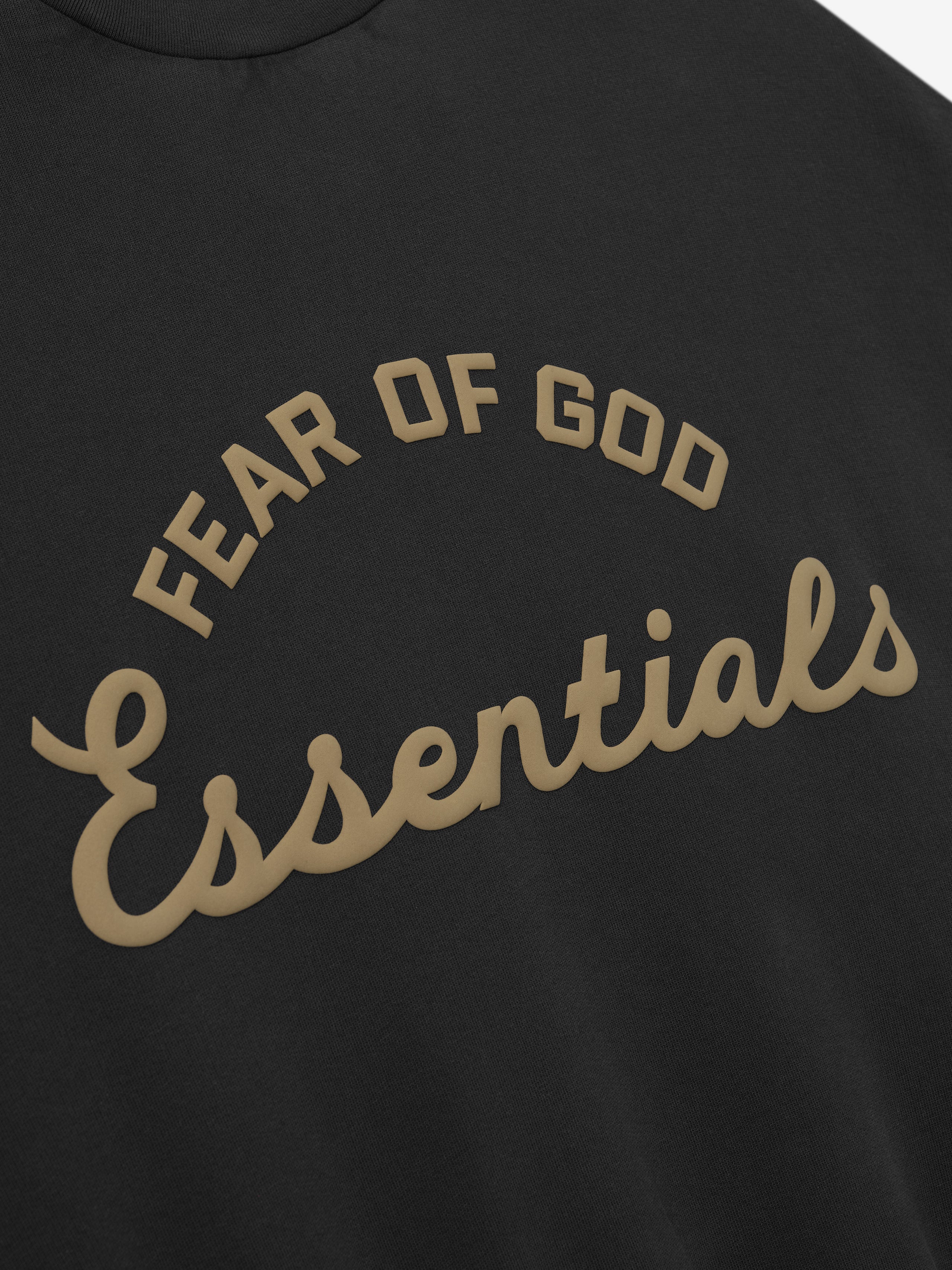 close-up of black kids crewneck sweatshirt with Fear of God Essentials training logo puff-printed in tan on front
