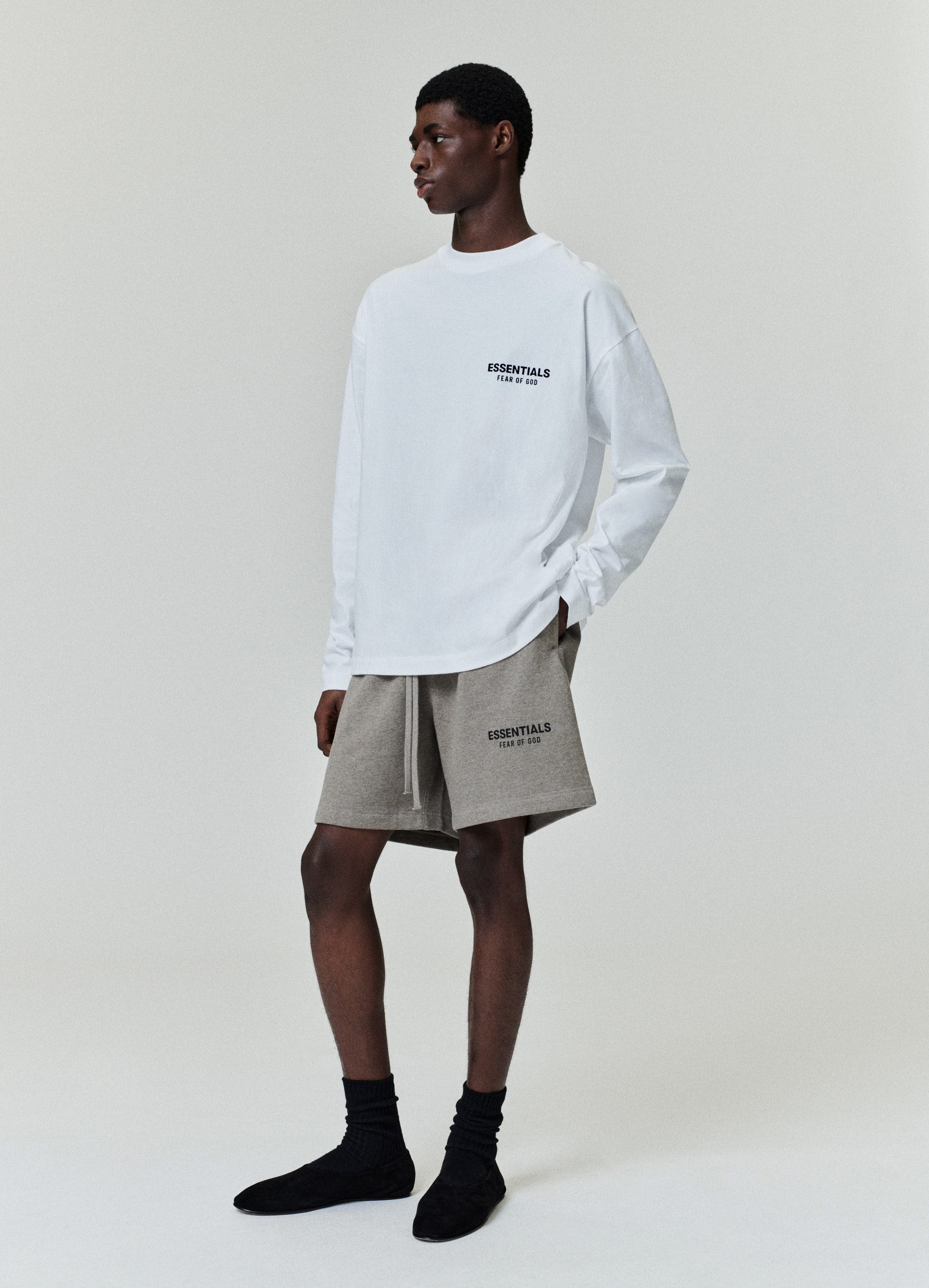 Side profile of model wearing white Classic Long Sleeve Tee with ESSENTIALS Fear of God logo, image A10_A4_3403.jpg gallery 0