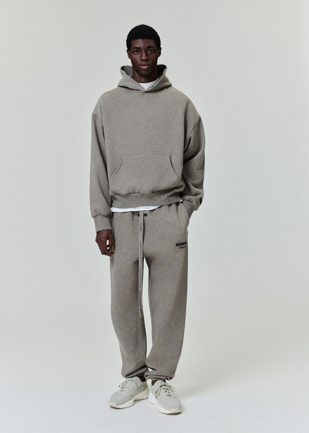 front view of beige Essentials Classic Hoodie and matching sweatpants in relaxed fit on male model