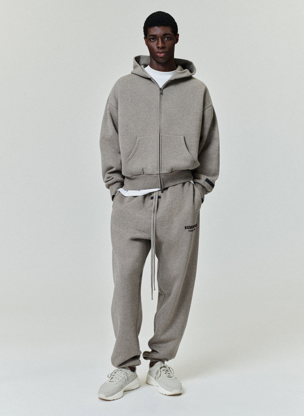 Taupe full-zip hoodie with hood, front pockets, and relaxed fit paired with matching sweatpants and white sneakers