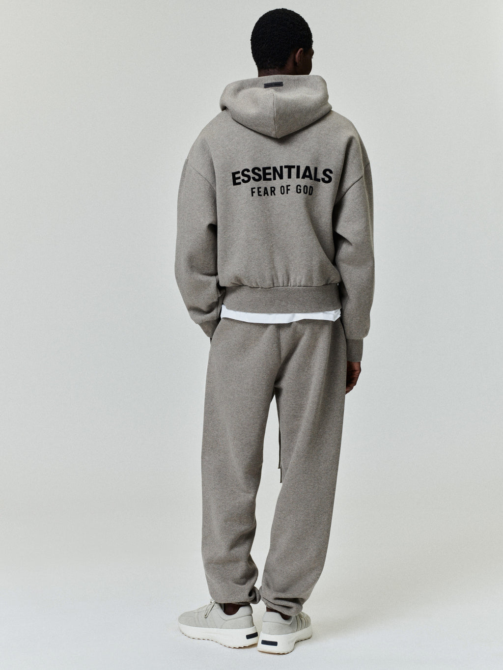 Taupe hooded sweatshirt and matching sweatpants with elastic cuffs and ESSENTIALS FEAR OF GOD branding on hoodie back