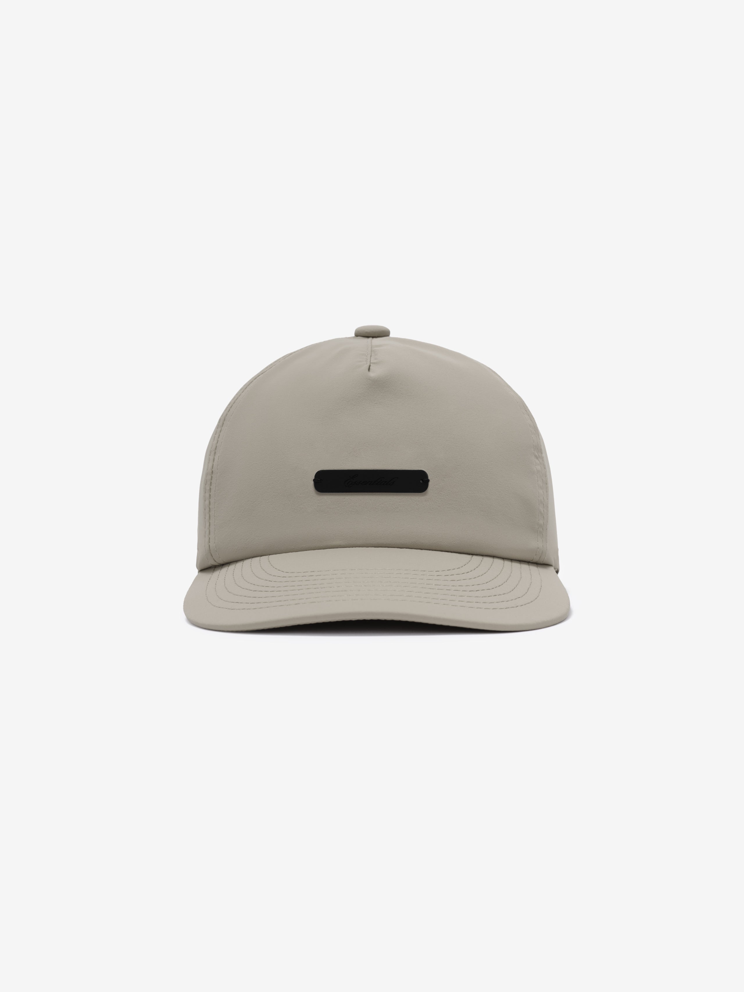 5 Panel Nylon Hat in muted beige featuring a sleek, minimal design with a small black rectangular logo plaque centered on the front panel for casual, versatile headwear.