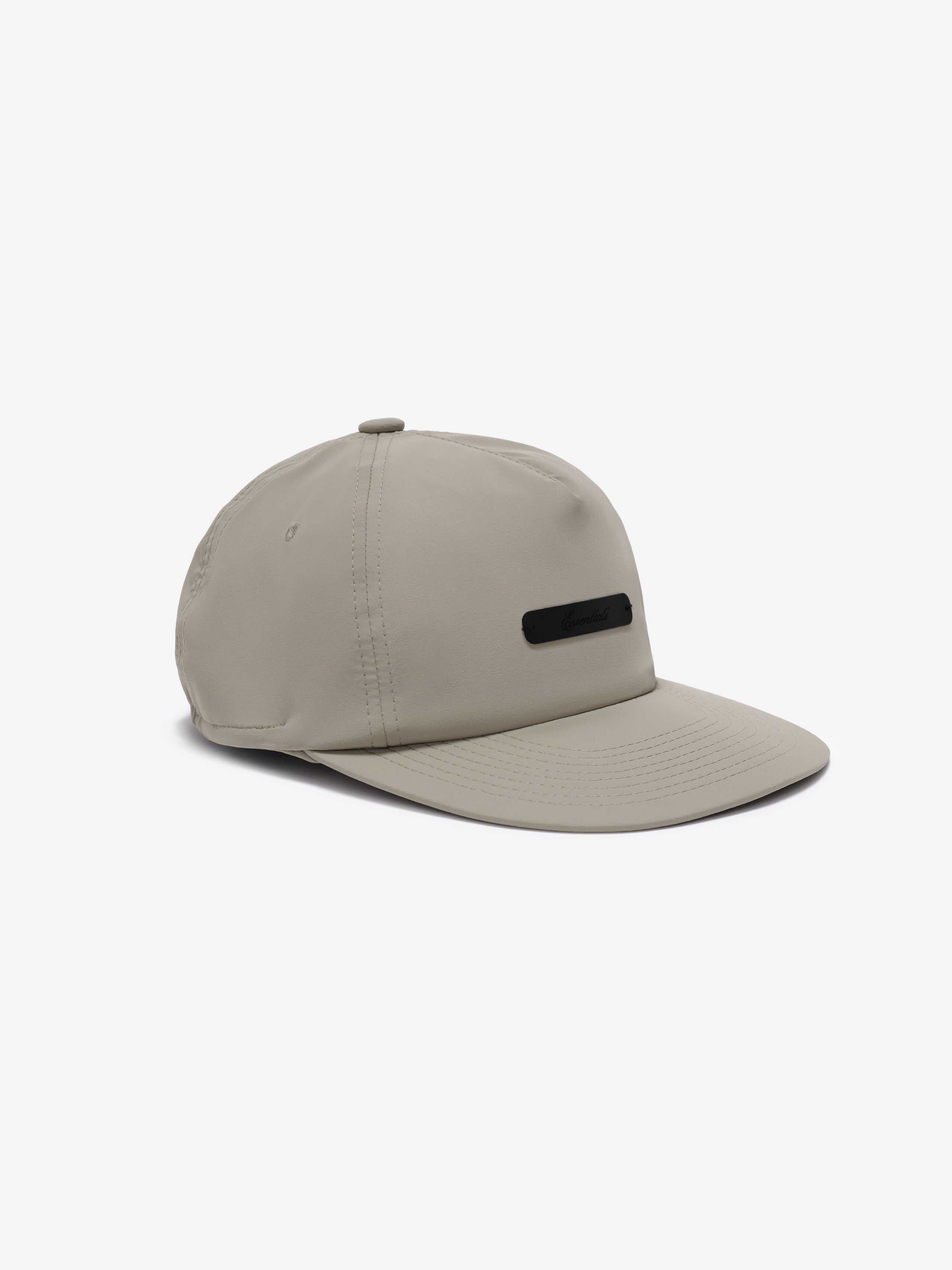 5 Panel Nylon Hat in a muted taupe color with a smooth finish, featuring a subtle black rectangular logo plaque on the front for understated casual styling.