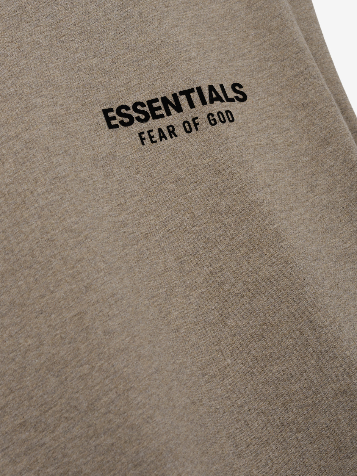 Essentials FW26 Classic Cut-Off taupe fabric close-up featuring a black Essentials Fear of God logo in a detailed Tops product view