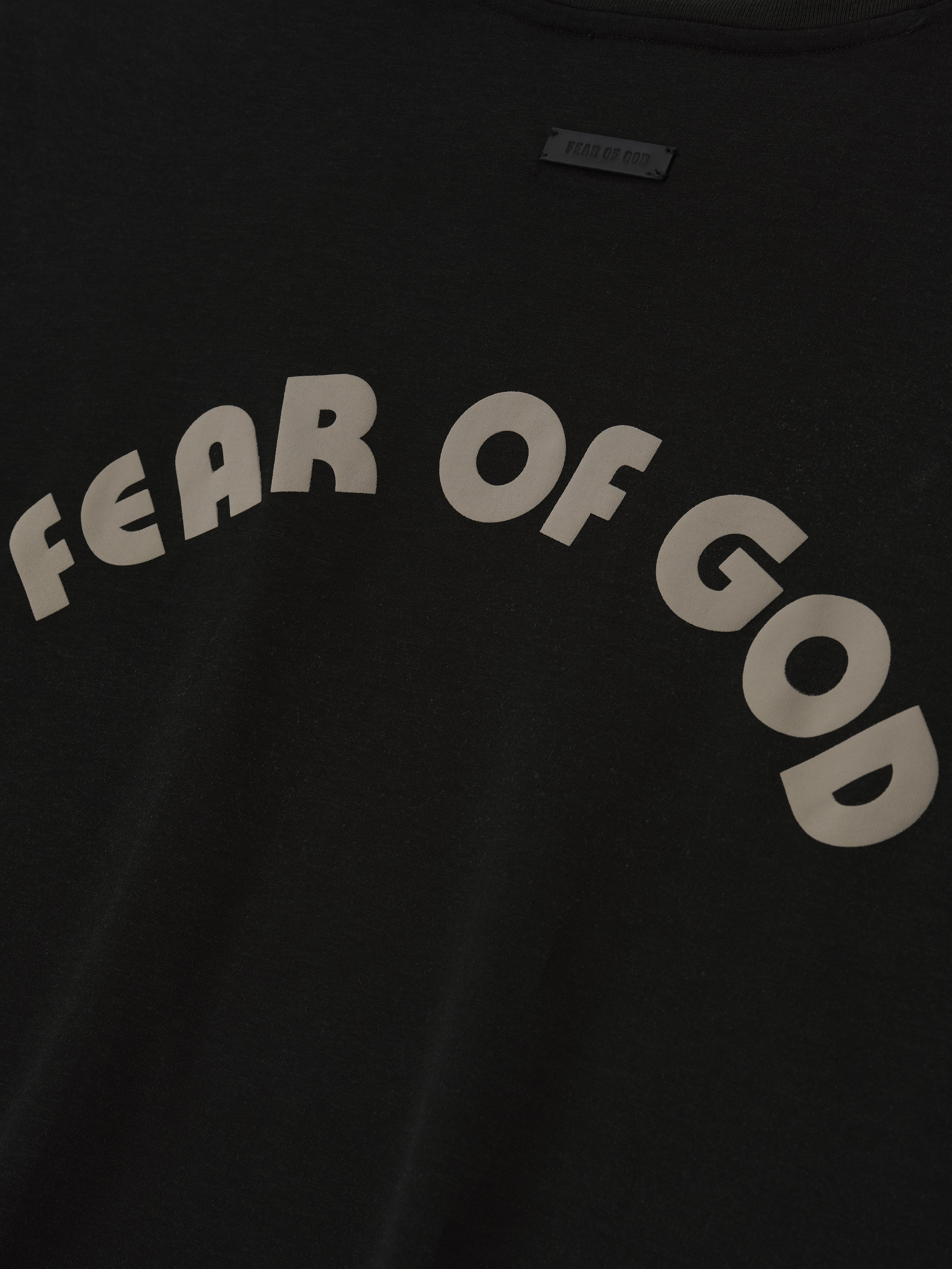 black cotton-rayon tee with large arched "FEAR OF GOD" lettering in off-white across the front chest