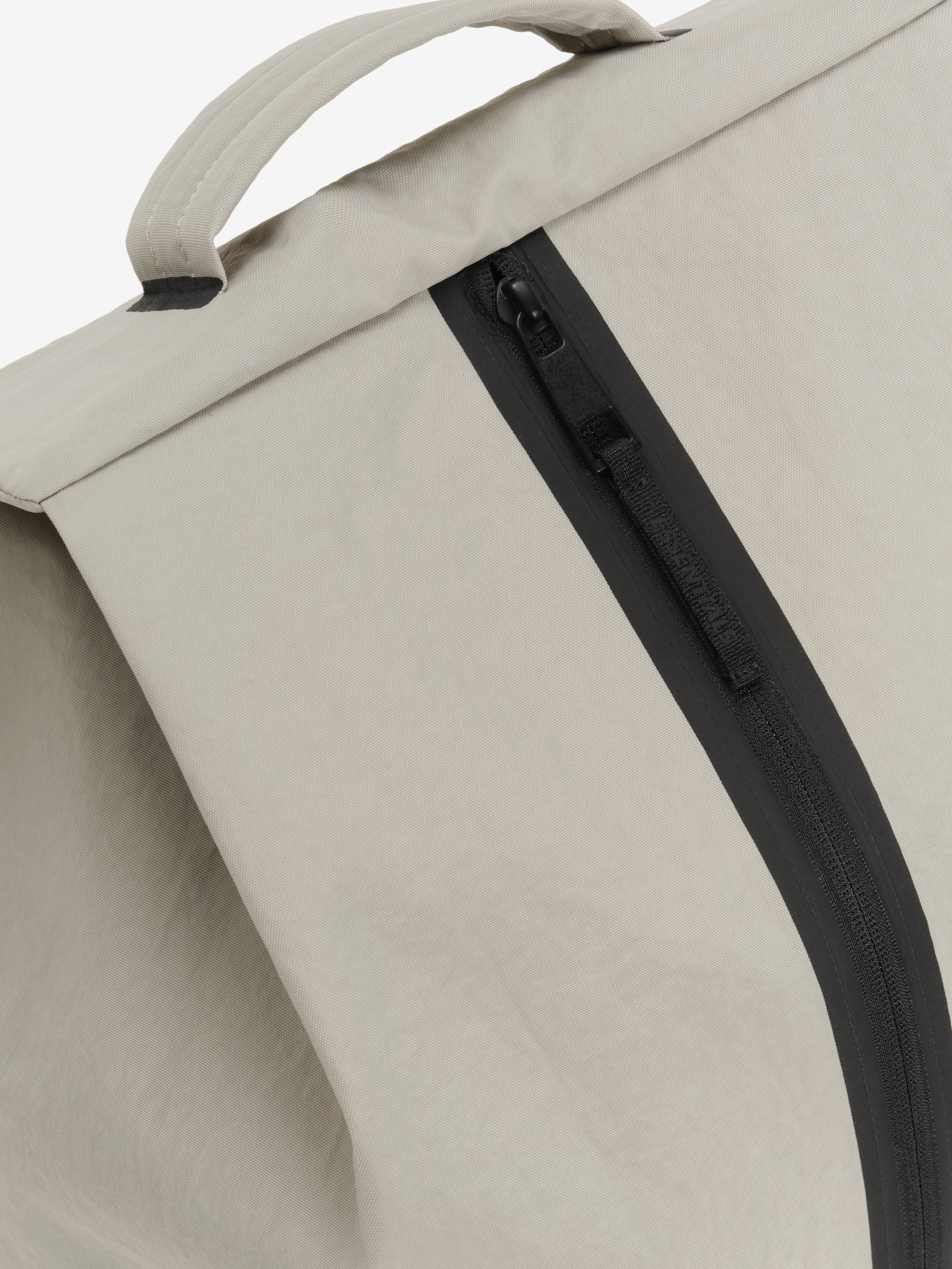 Sports Duffel in light gray close up showing a padded top handle and curved black zipper on smooth textured fabric against a clean background