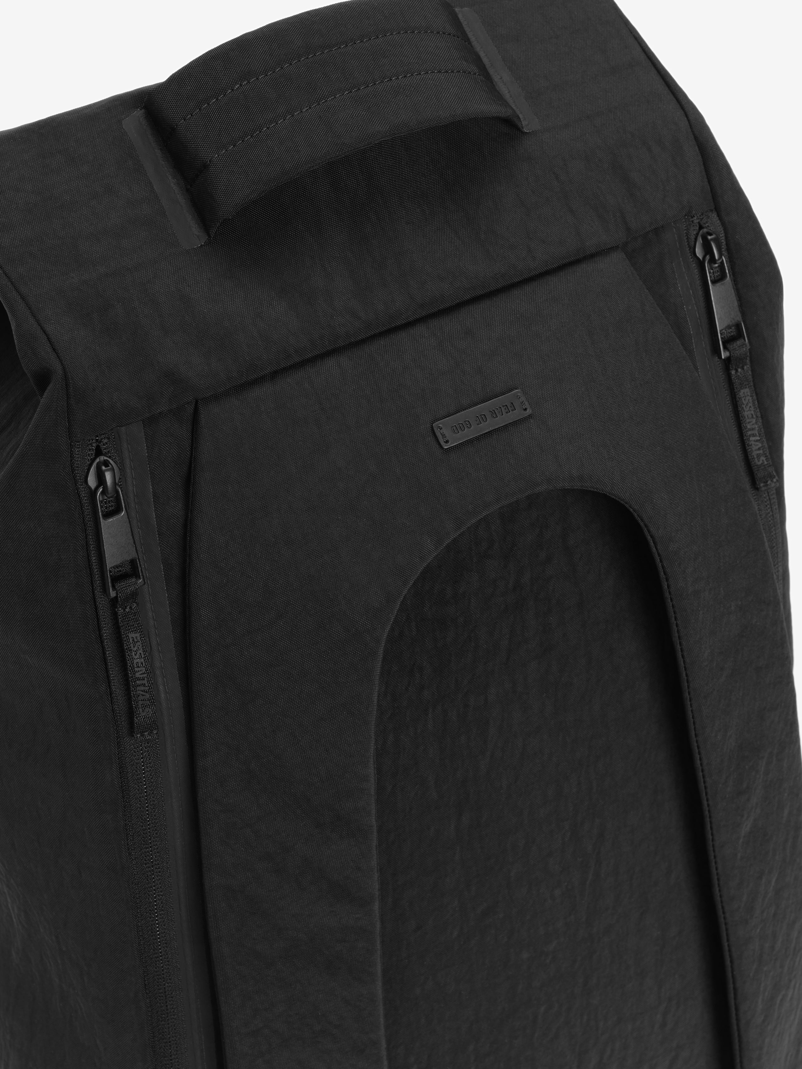 Sports Duffel in black featuring a padded top handle dual side zippers a large curved front pocket and a subtle rectangular logo patch on textured fabric