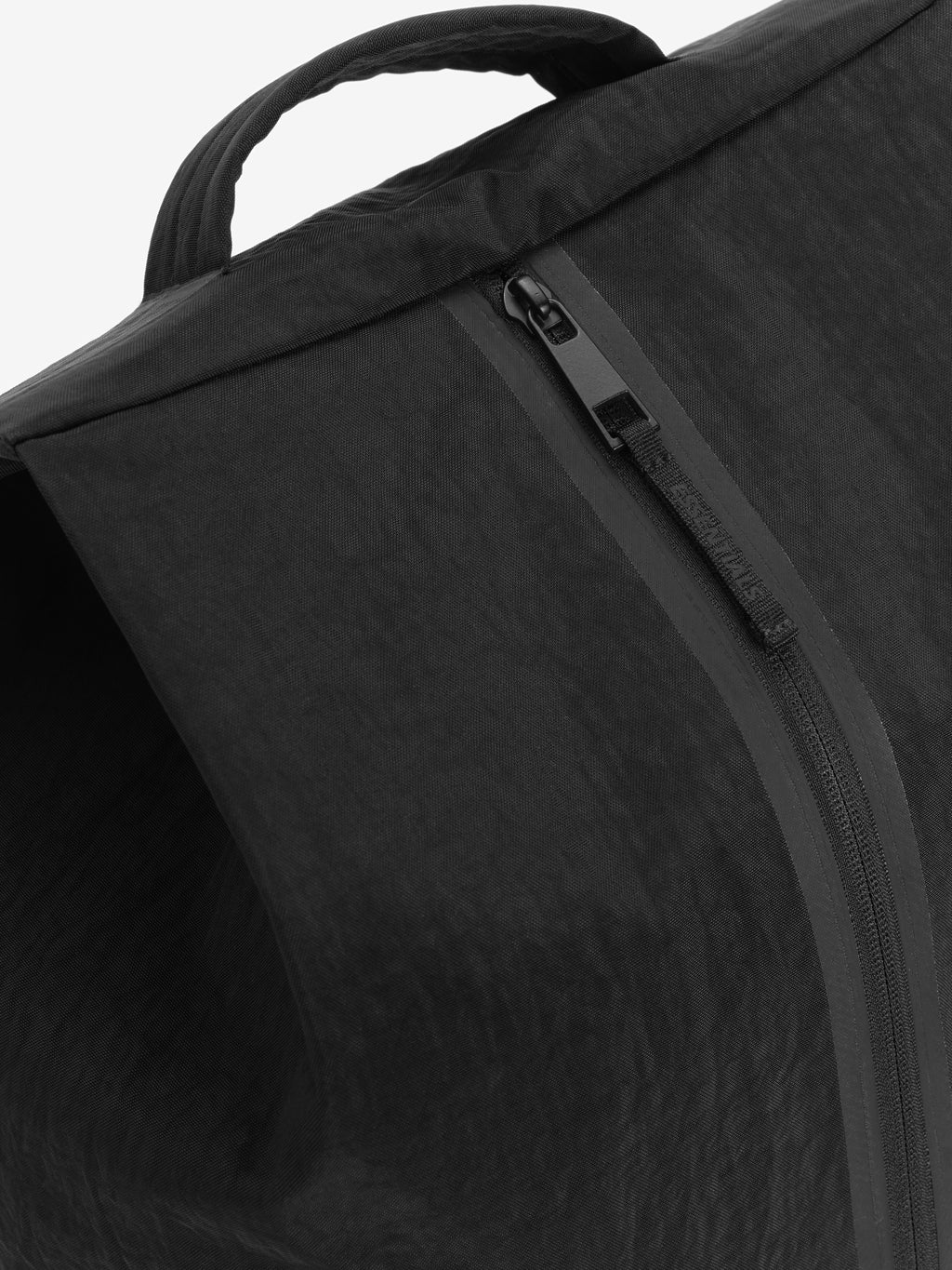 Sports Duffel in black close up showing a padded carry handle and curved zipper on textured fabric against a clean white background
