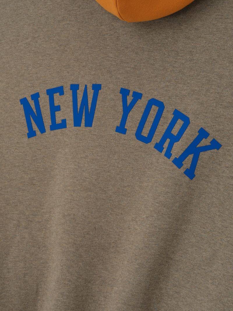 Close-up of brown Knicks Sport Hoodie featuring blue arched NEW YORK text and partial view of contrasting orange hood EoJPMCEQ.jpg