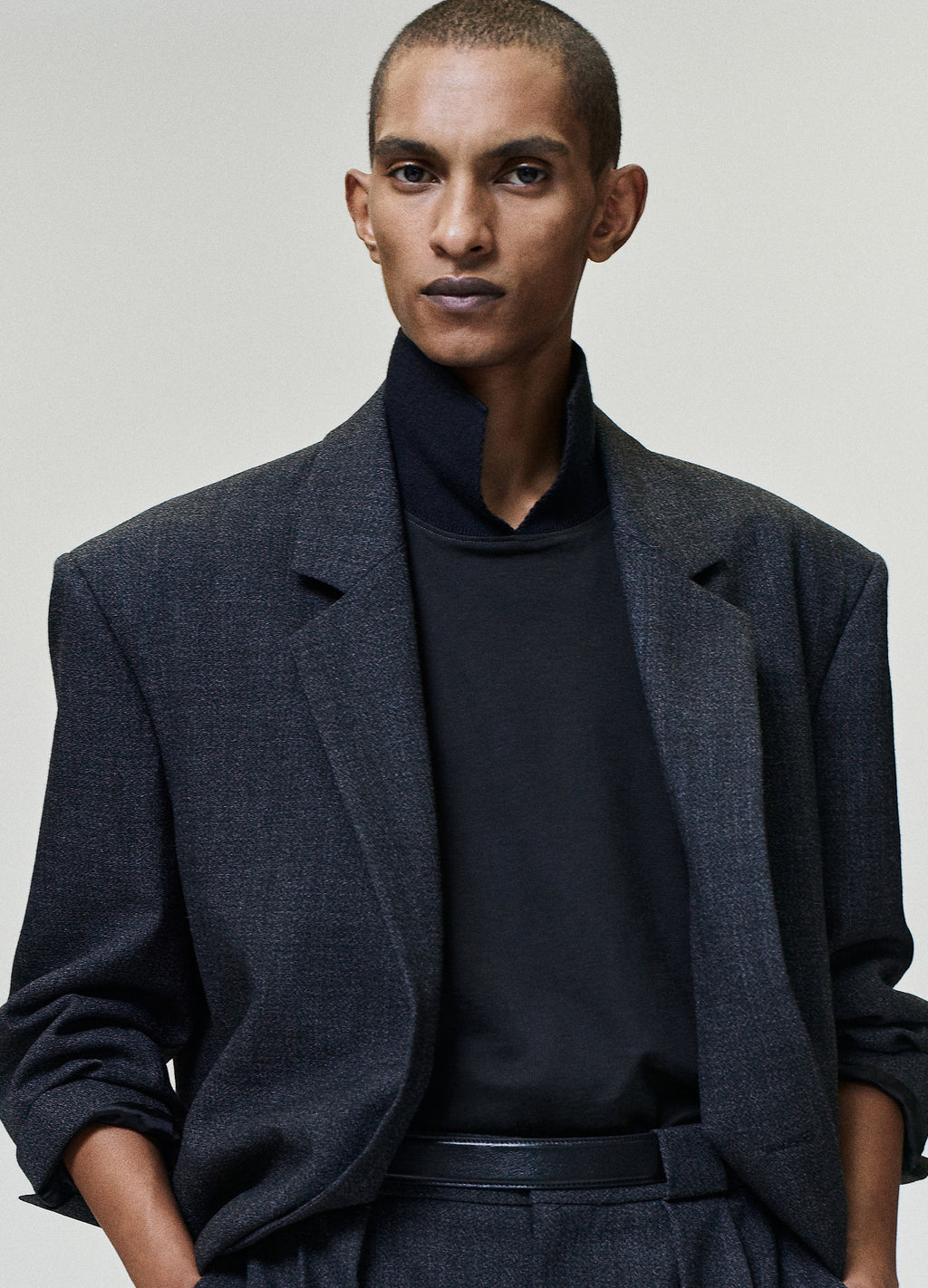 Wool Ripstop Pullover Shirt worn in black with a high neckline and relaxed fit layered beneath a dark textured blazer as Tops