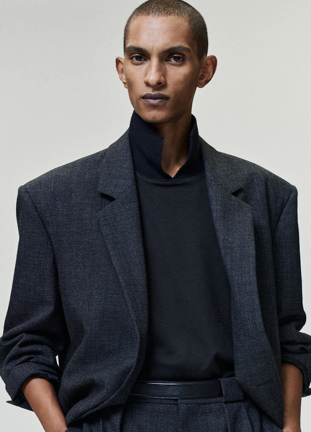 Wool Ripstop Pullover Shirt worn in black with a high neckline and relaxed fit layered beneath a dark textured blazer as Tops