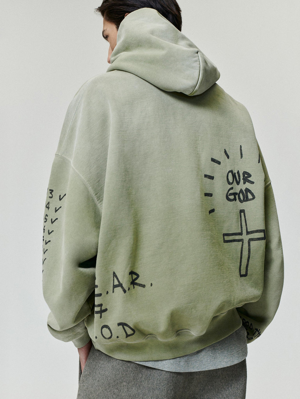 Hand Written Hoodie in sage green with handwritten graphics and cross artwork on the back and sleeves shown on a model as Tops