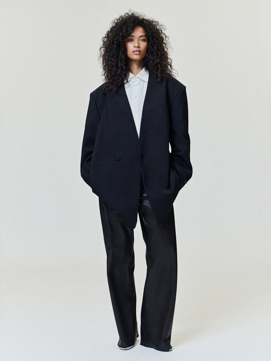 Easy Care Wool Lapelless Mid-length Jacket worn in black over a white shirt with a relaxed silhouette and long sleeves styled with dark trousers as Outerwear
