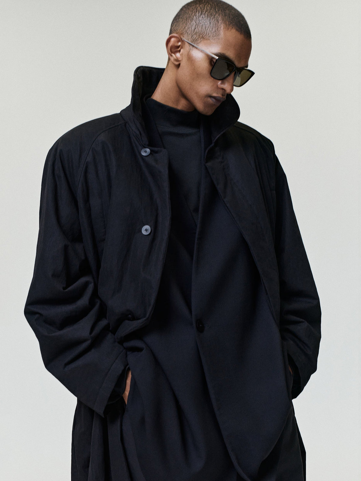 Merino Double Knit Mockneck Sweater in black worn beneath a dark jacket with its high mock neckline and long sleeves visible as Tops