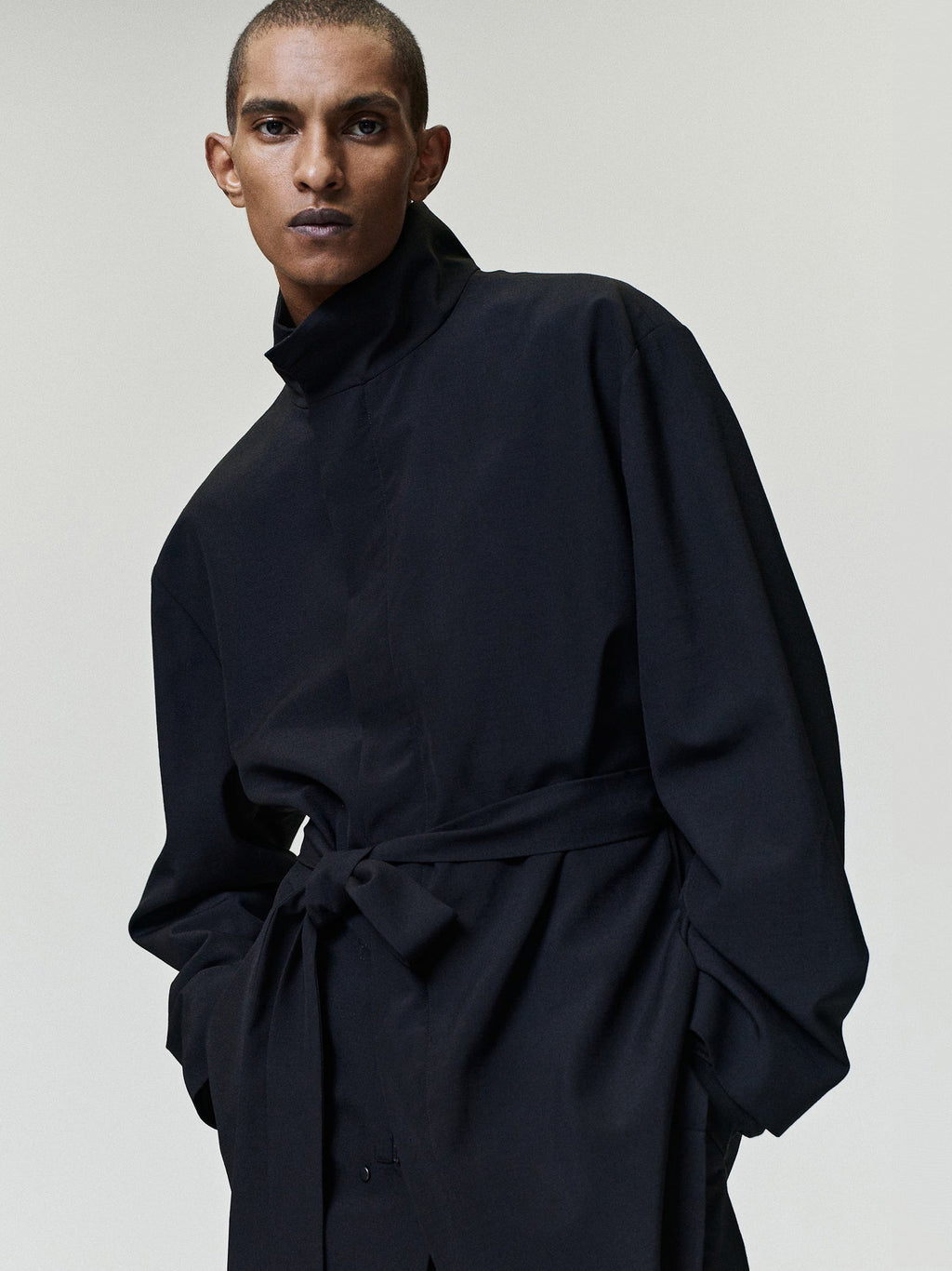 Wool Ripstop Leisure Jacket in black worn by a model with a raised collar long sleeves and tied waist sash as Outerwear