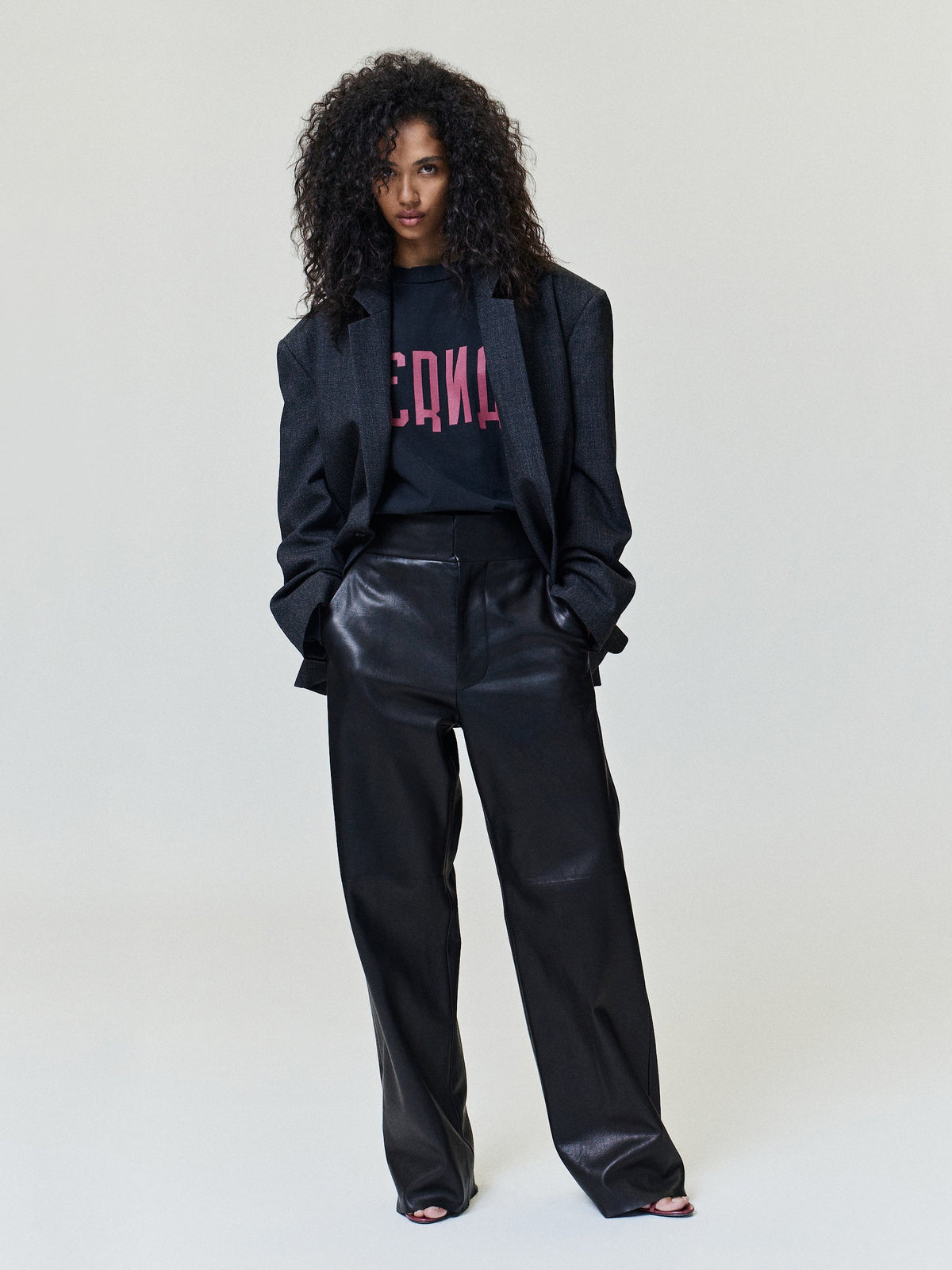 Eternal Tee in black with bold pink Eternal lettering worn under a dark blazer by a model as Tops