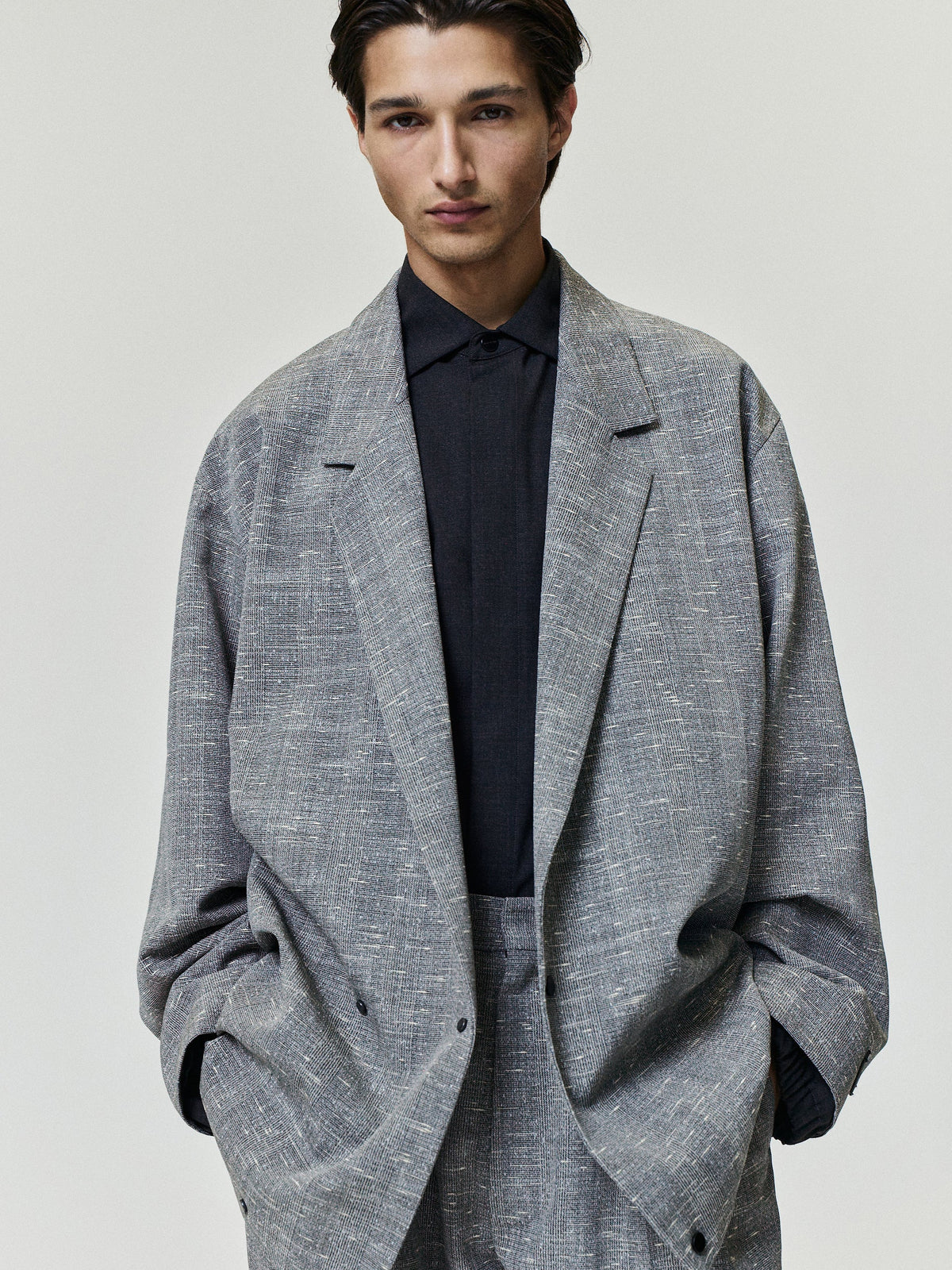 Slub Wool Cotton Relaxed Jacket worn in textured gray with notched lapels patch pockets long sleeves and an oversized fit over a dark shirt as Outerwear