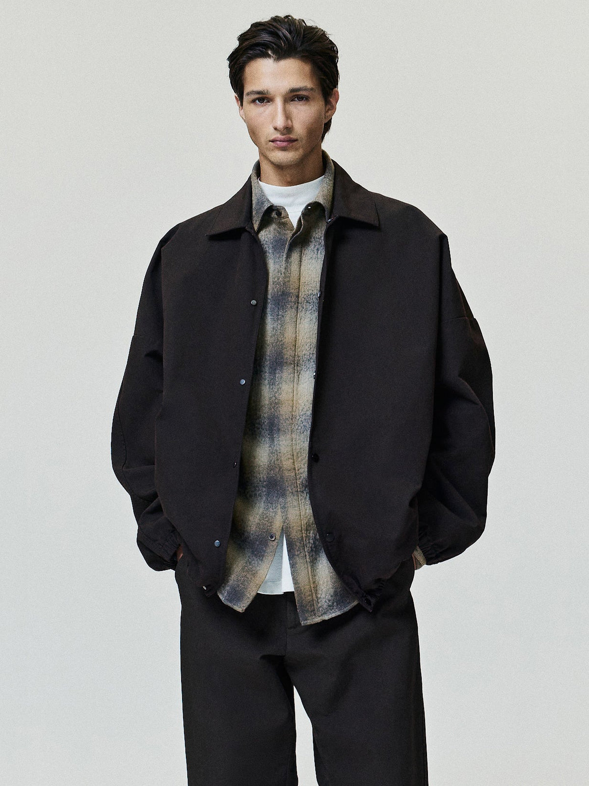 Cotton Wool Flannel Check Shirt in brown and beige plaid worn under a dark jacket showing pointed collar long sleeves button front and curved hem as Tops