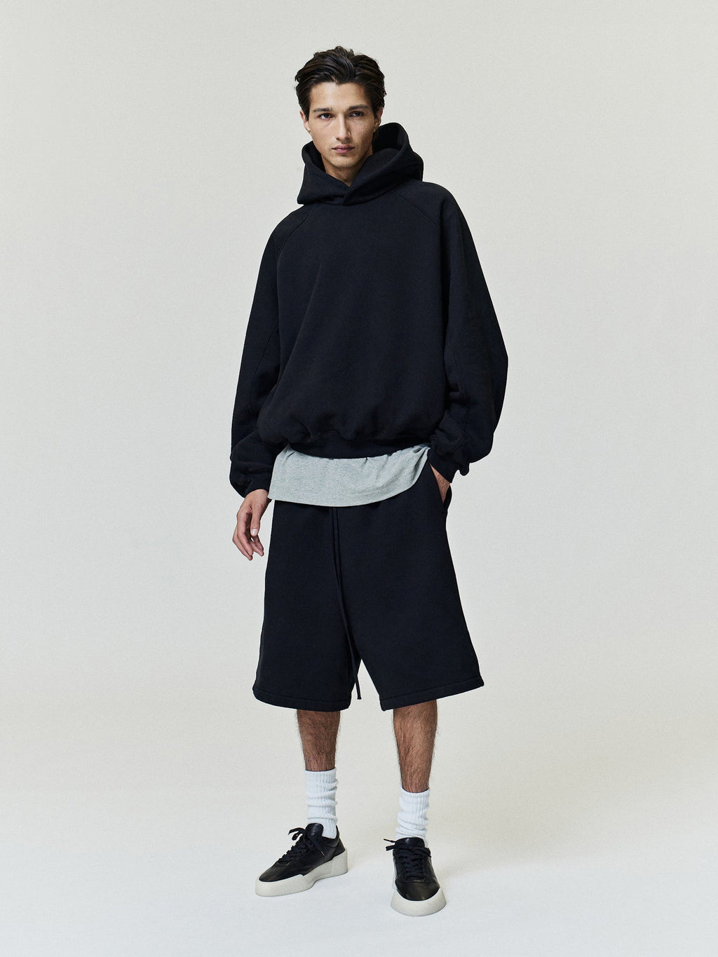 Fleece Basketball Shorts modeled in black with a relaxed knee length fit elastic waistband and side pockets styled with sneakers as Bottoms