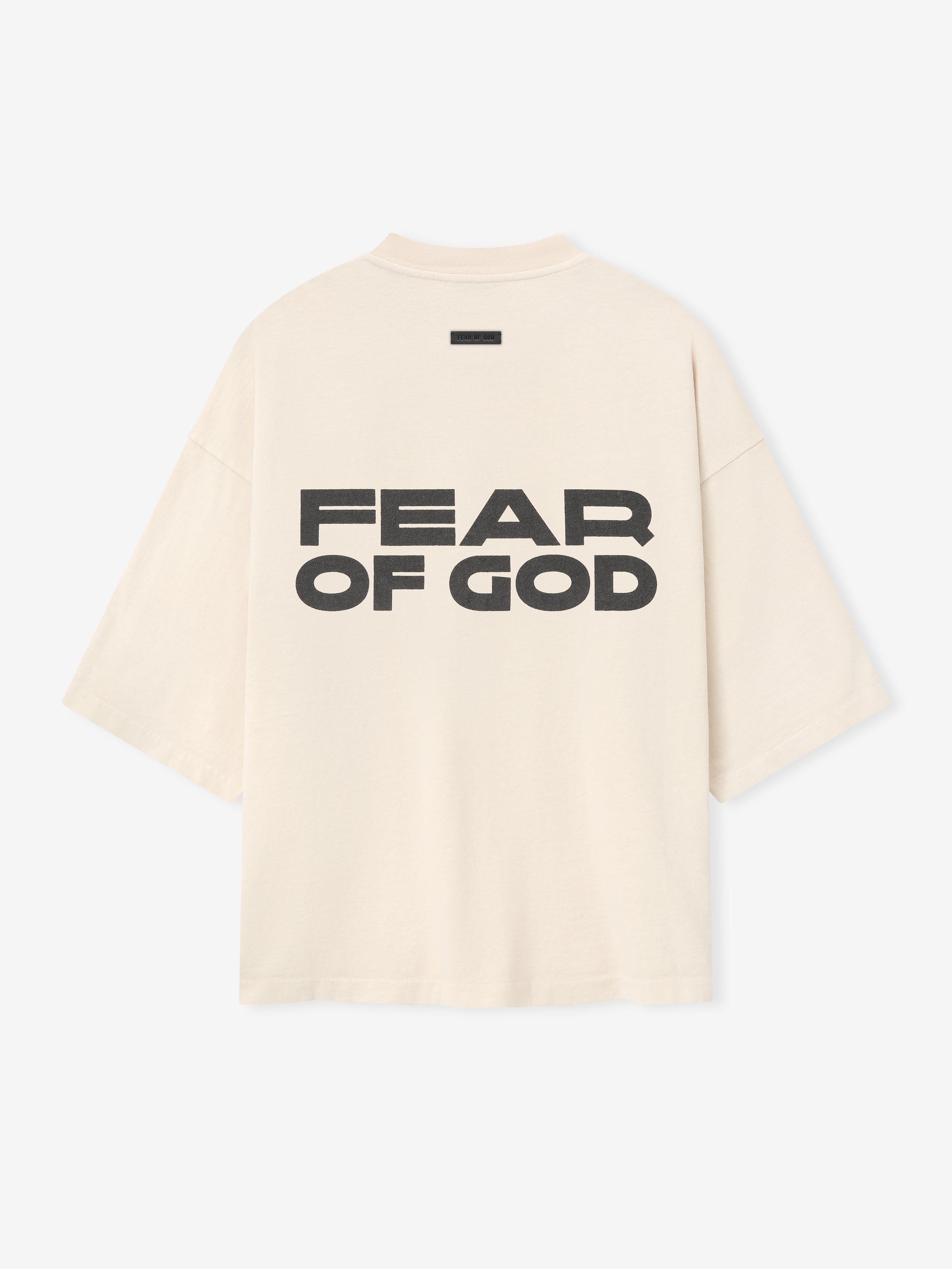 Relaxed Disciple Tee in a soft off-white shade featuring bold black “FEAR OF GOD” lettering across the back, crafted from cotton with an oversized fit and dropped shoulders for a casual tops style.