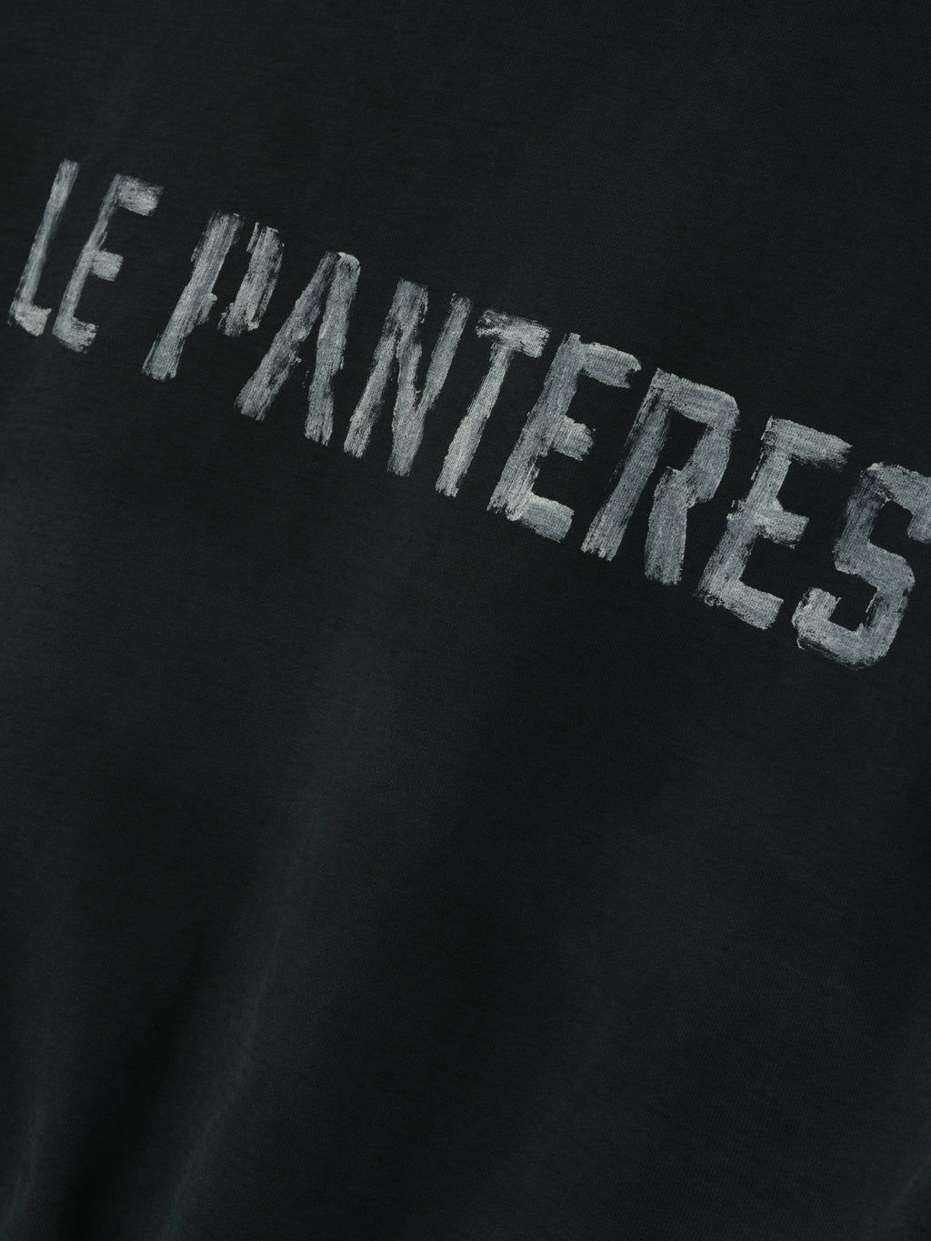 Le Panteres Hoodie in black featuring distressed white lettering across the fabric, crafted from soft material for a relaxed and stylish outerwear look.