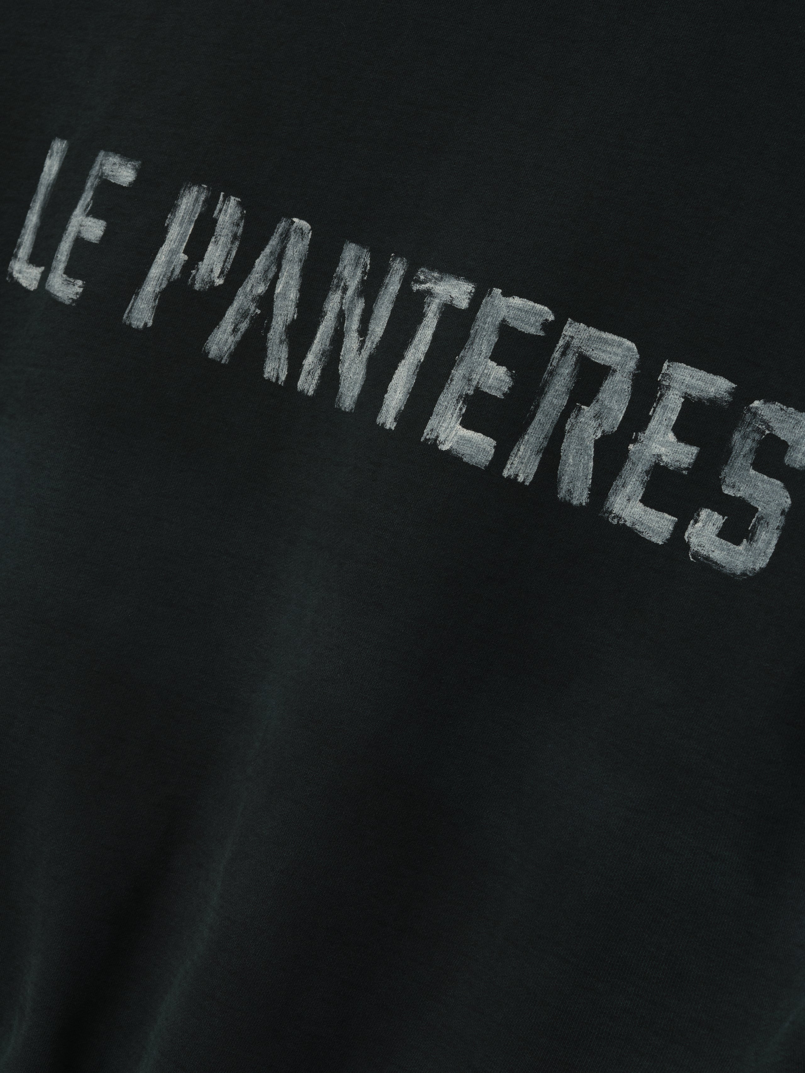 Le Panteres Hoodie in black featuring distressed white lettering across the fabric, crafted from soft material for a relaxed and stylish outerwear look.