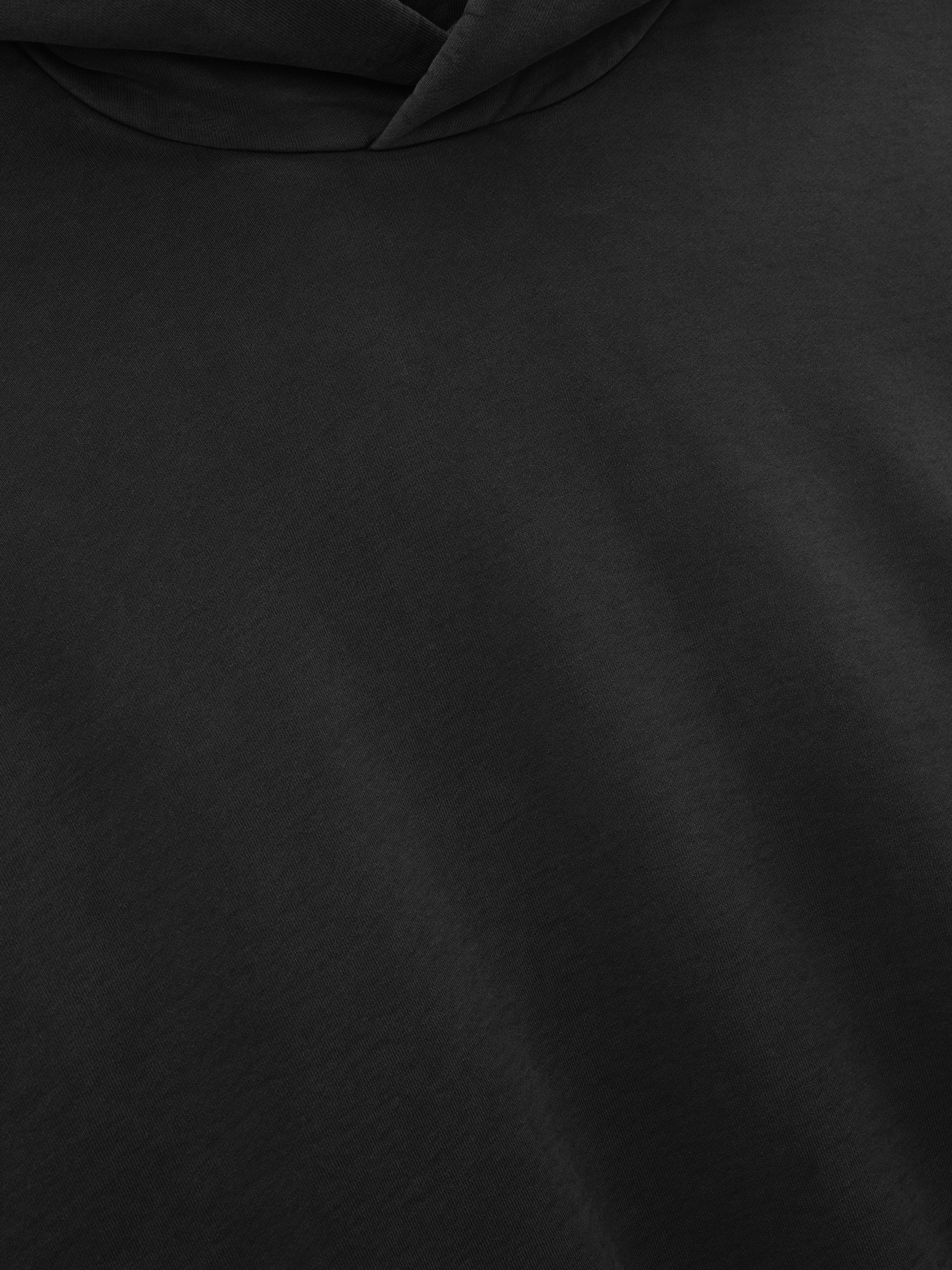 Close-up detail of the soft black fabric and hood of the Washed Hoodie, highlighting its smooth texture and subtle fading for a worn-in, casual outerwear look.