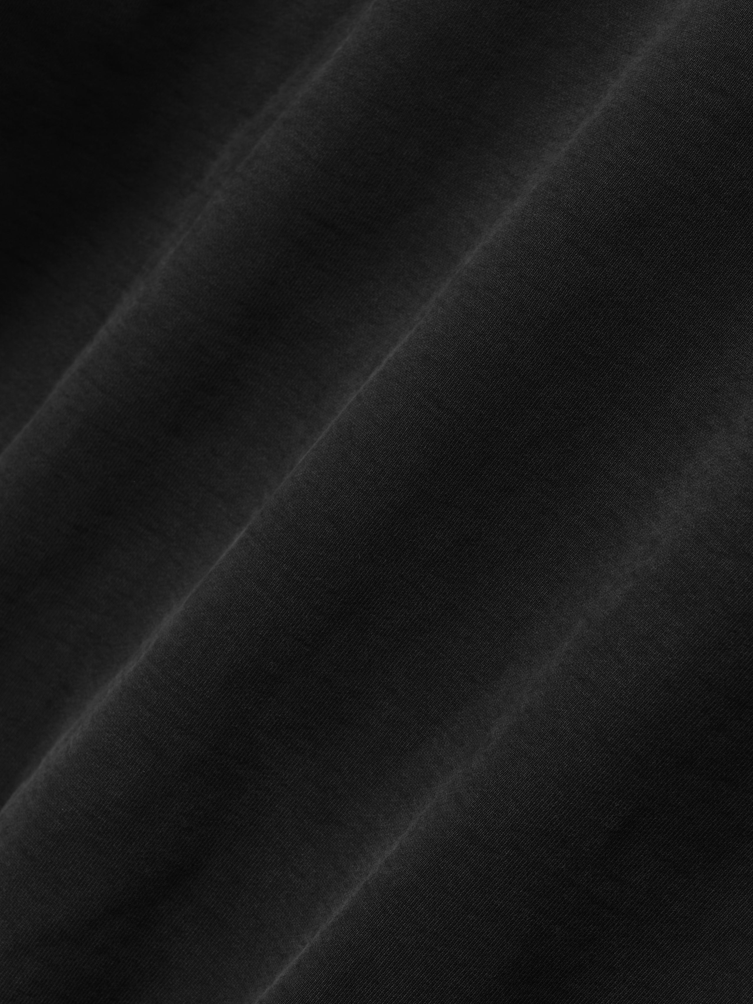 Close-up of the black fabric texture of the Washed Hoodie, highlighting the soft, smooth surface and subtle variations in shading for a refined casual outerwear look.