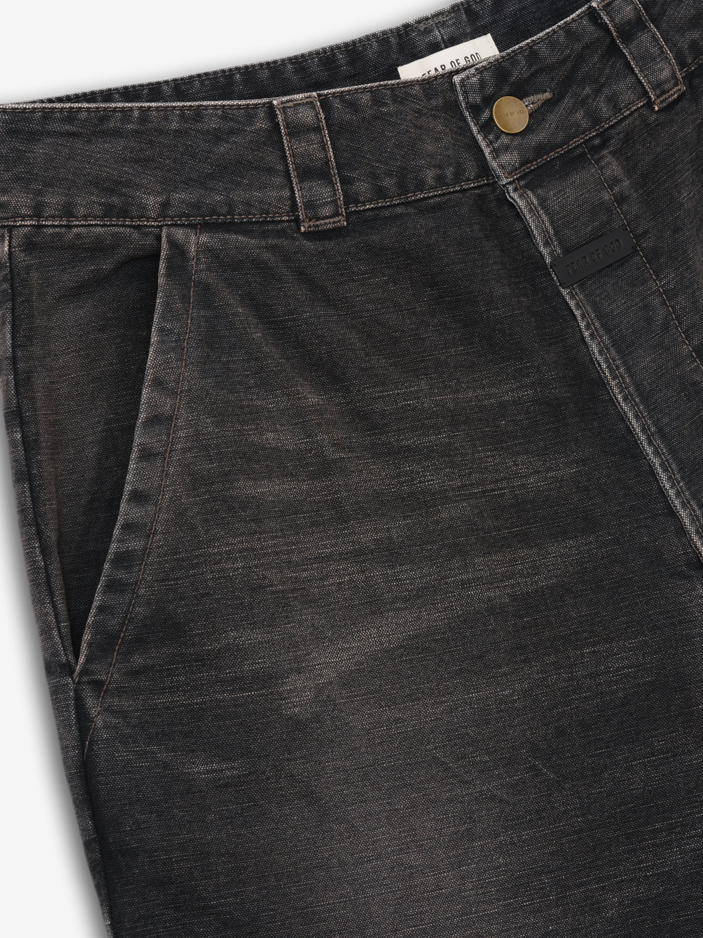 close-up of black washed cotton canvas utility pants waistband with side pocket and antique brass button closure