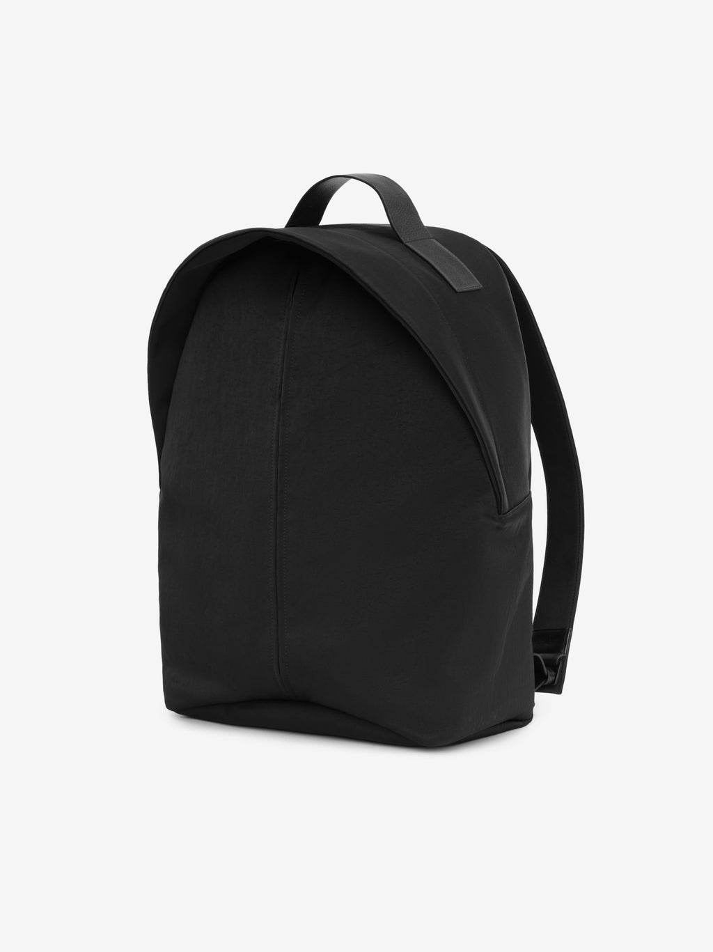 black technical nylon backpack with smooth rounded silhouette and leather top handle viewed at an angle