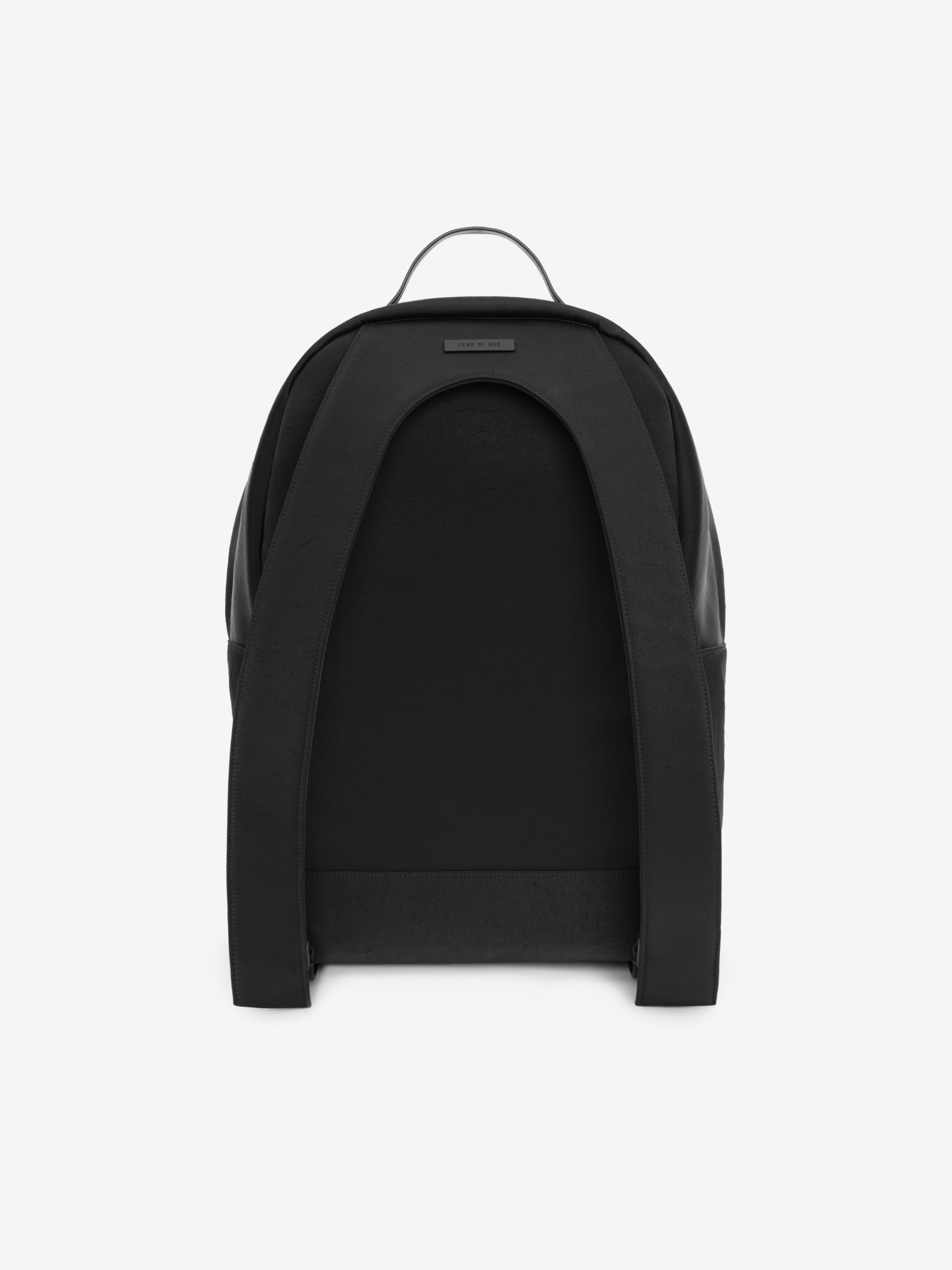 rear view of black technical nylon backpack with padded straps and leather top handle against white background