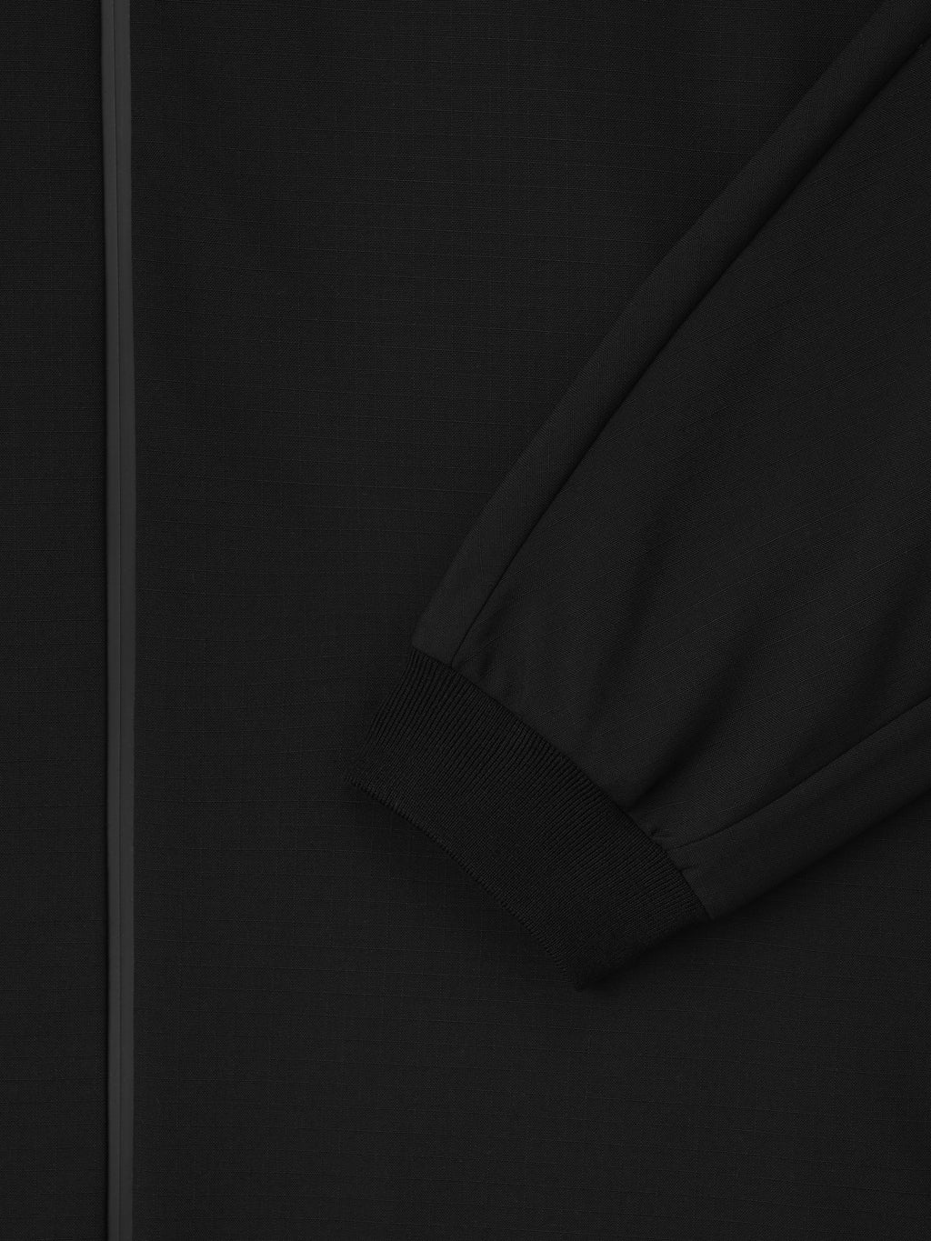 close-up of black wool ripstop fabric with subtle grid texture and elastic cuff on kimono sleeve