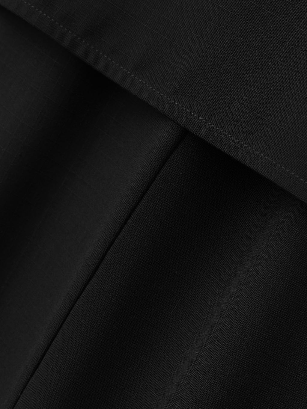 close-up of black lightweight wool ripstop fabric with fine grid texture and detailed stitching on shirt dress panel